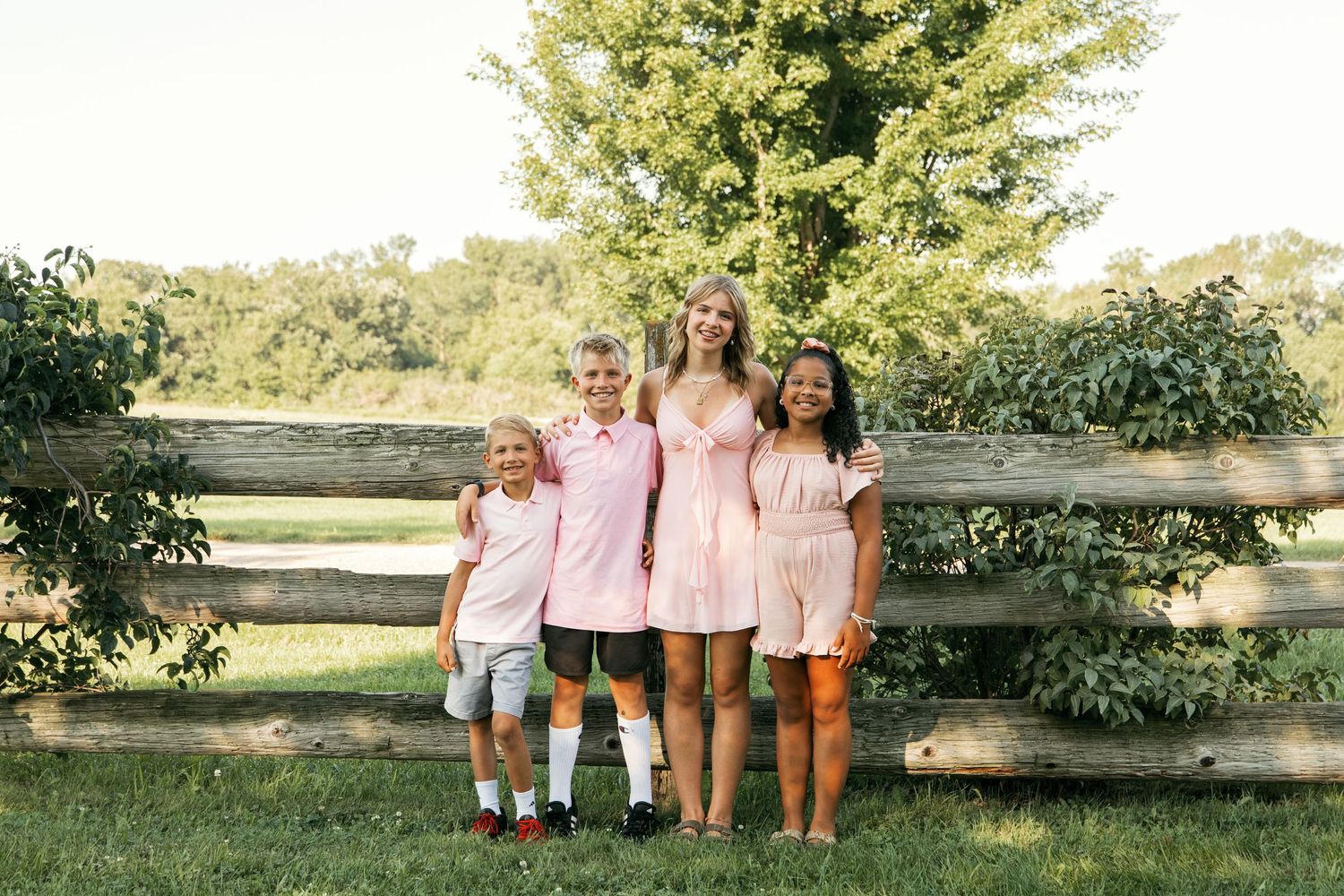 A series of six outdoor family photos taken in a natural setting with rustic wooden fences and greenery in the background.
