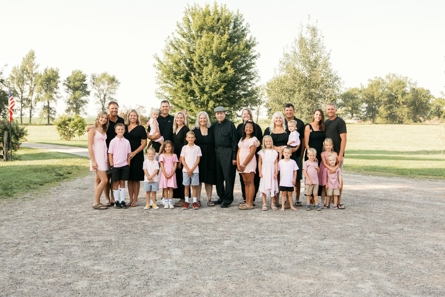Large group poses together outdoors for family photos in coordinated outfits on a sunny day.