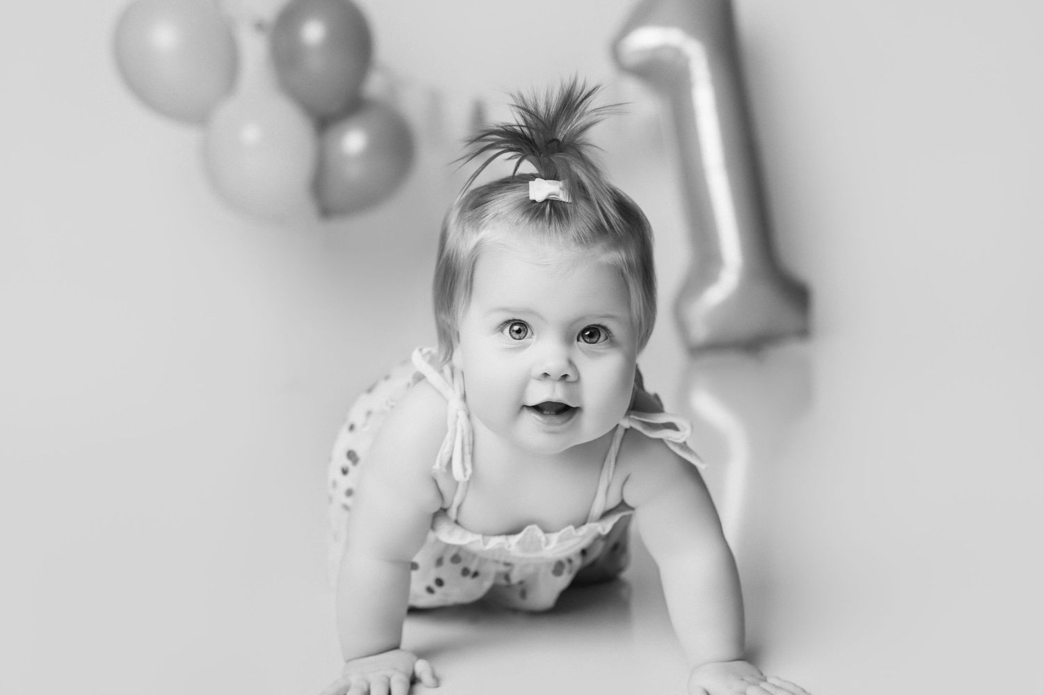 First birthday photoshoot with silver balloons and party decorations on white background.