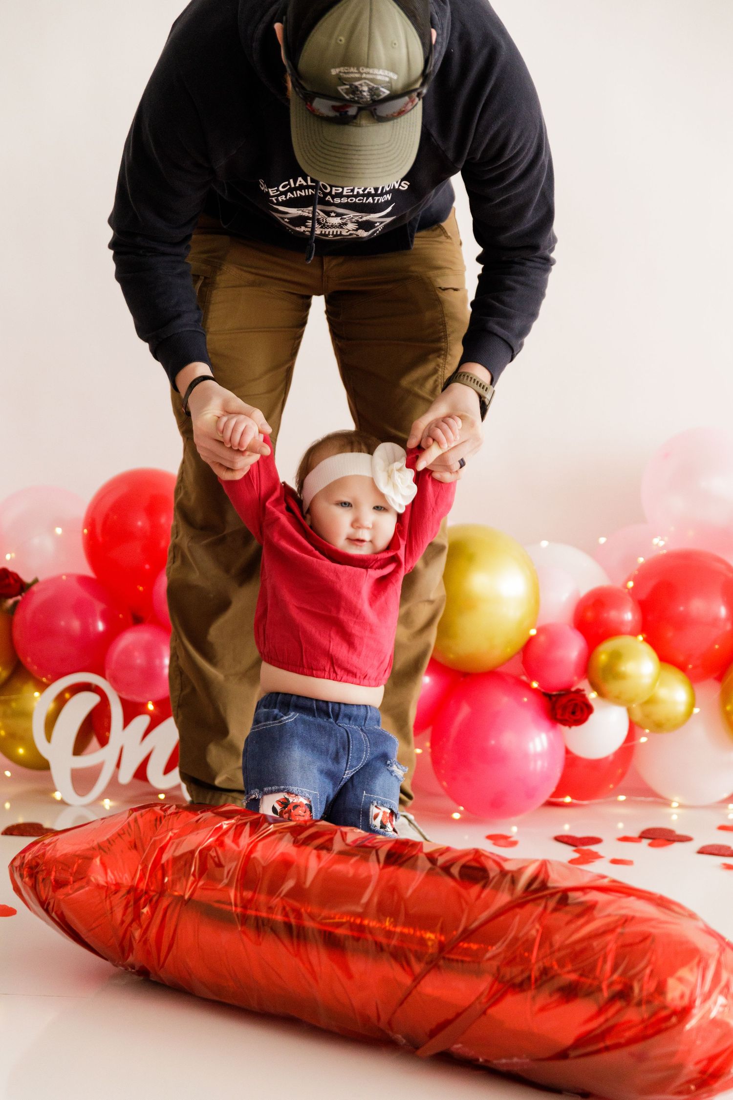 Red and gold balloon decorations with a festive Valentine's day setup against a white backdrop.