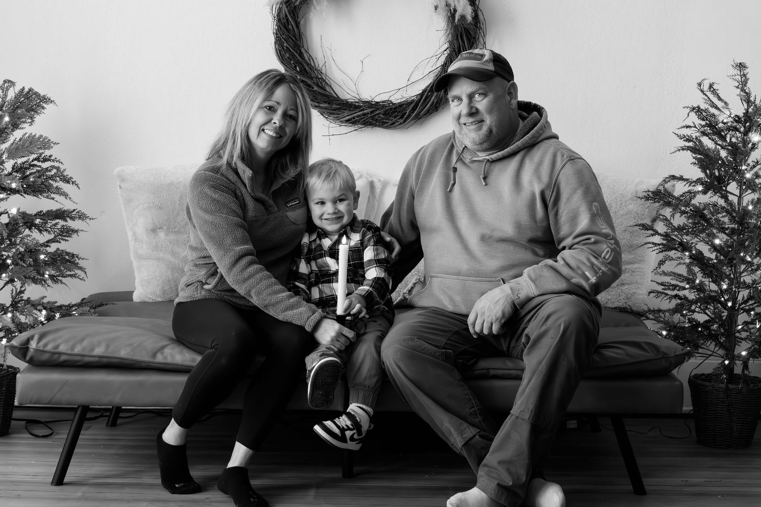 Black and white family holiday portraits taken in front of decorated Christmas tree.