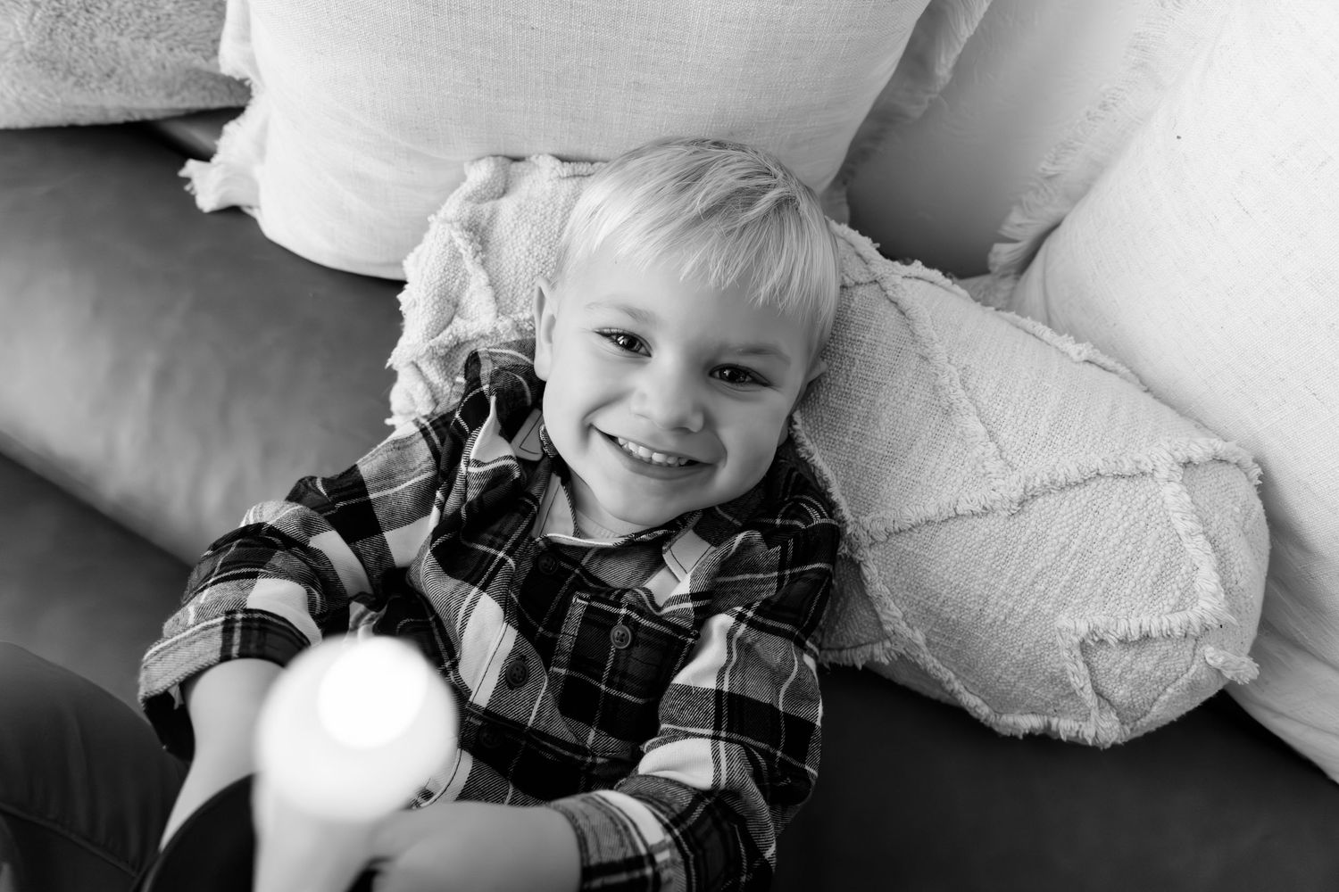 Black and white candid photo showing relaxed lifestyle moment on light furniture.