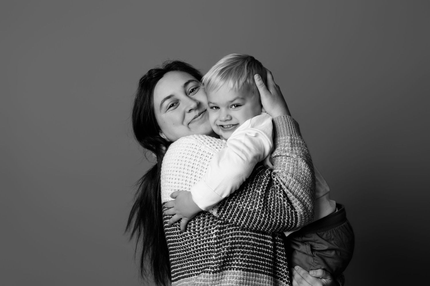 Black and white studio portraits showing tender family moments against a neutral backdrop.