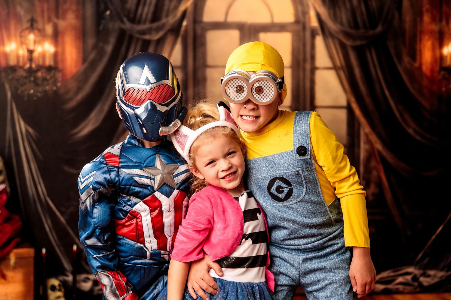 Three children in Halloween costumes pose together, dressed as Captain America, a Minion, and a princess.