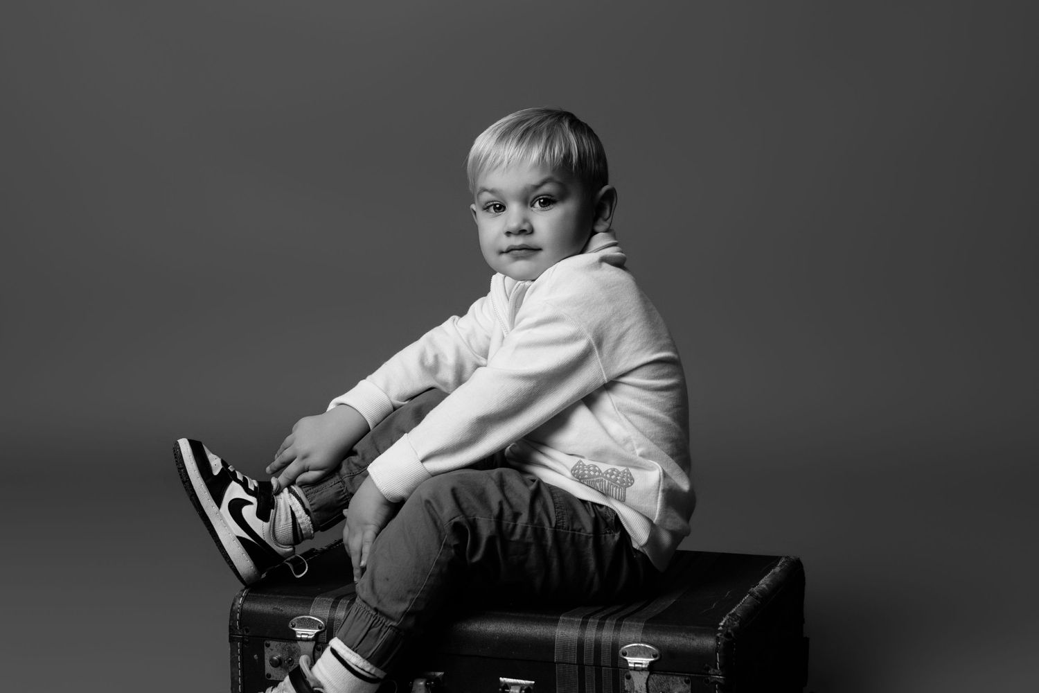 A child lounges on dark furniture during a professional photo session.