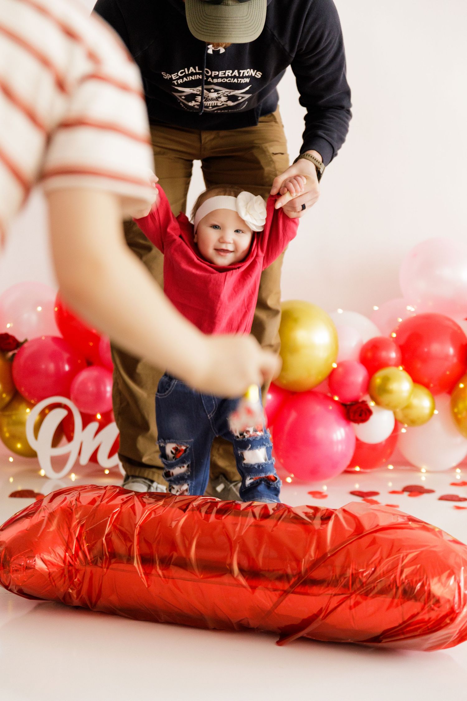 Red balloon arch setup with gold accents and decorative elements on white background.