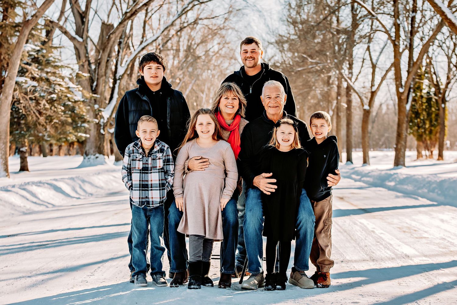 Group portrait in warm clothing standing on a snow-covered path with winter trees in the background.