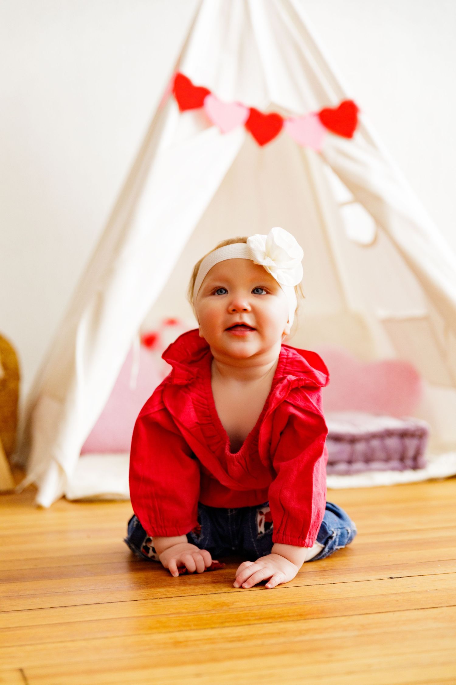 White teepee play tent with red heart banner and wooden floor setting.