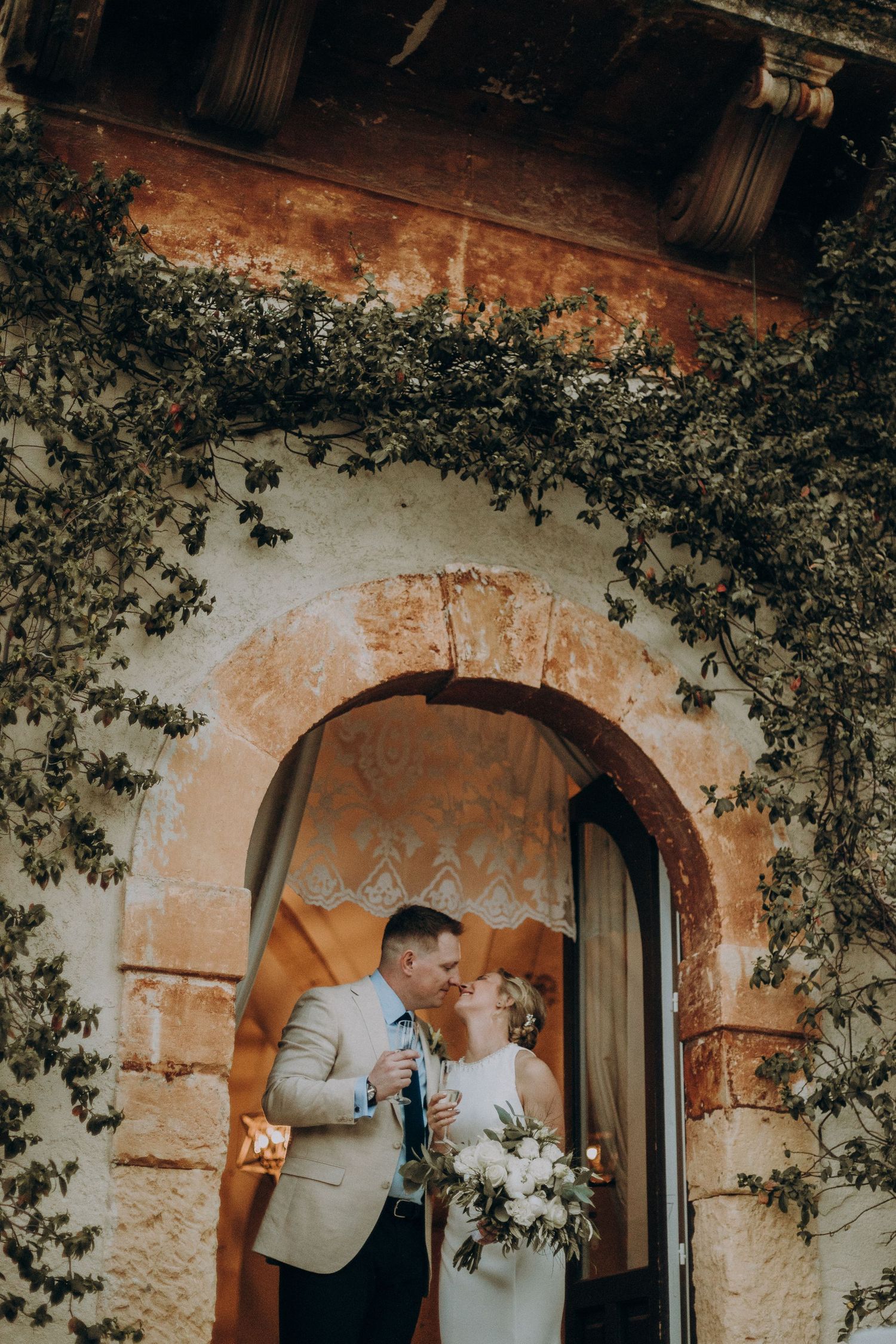 Bride and groom through traditional Sicilian village with rustic architecture and soft warm light for destination wedding photographer