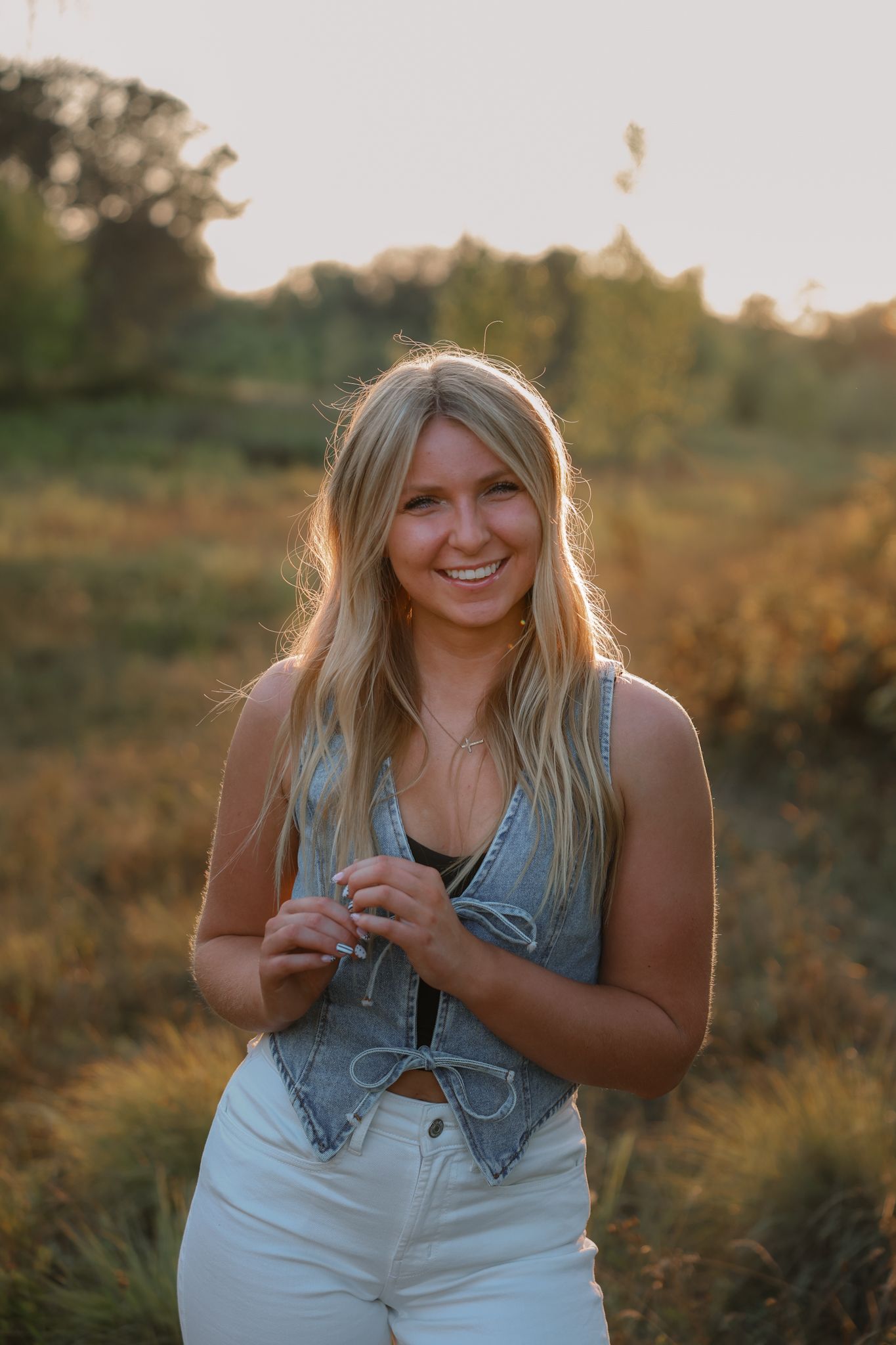 A series of photos taken at golden hour showing someone sitting in a grassy field wearing a denim vest and white pants.