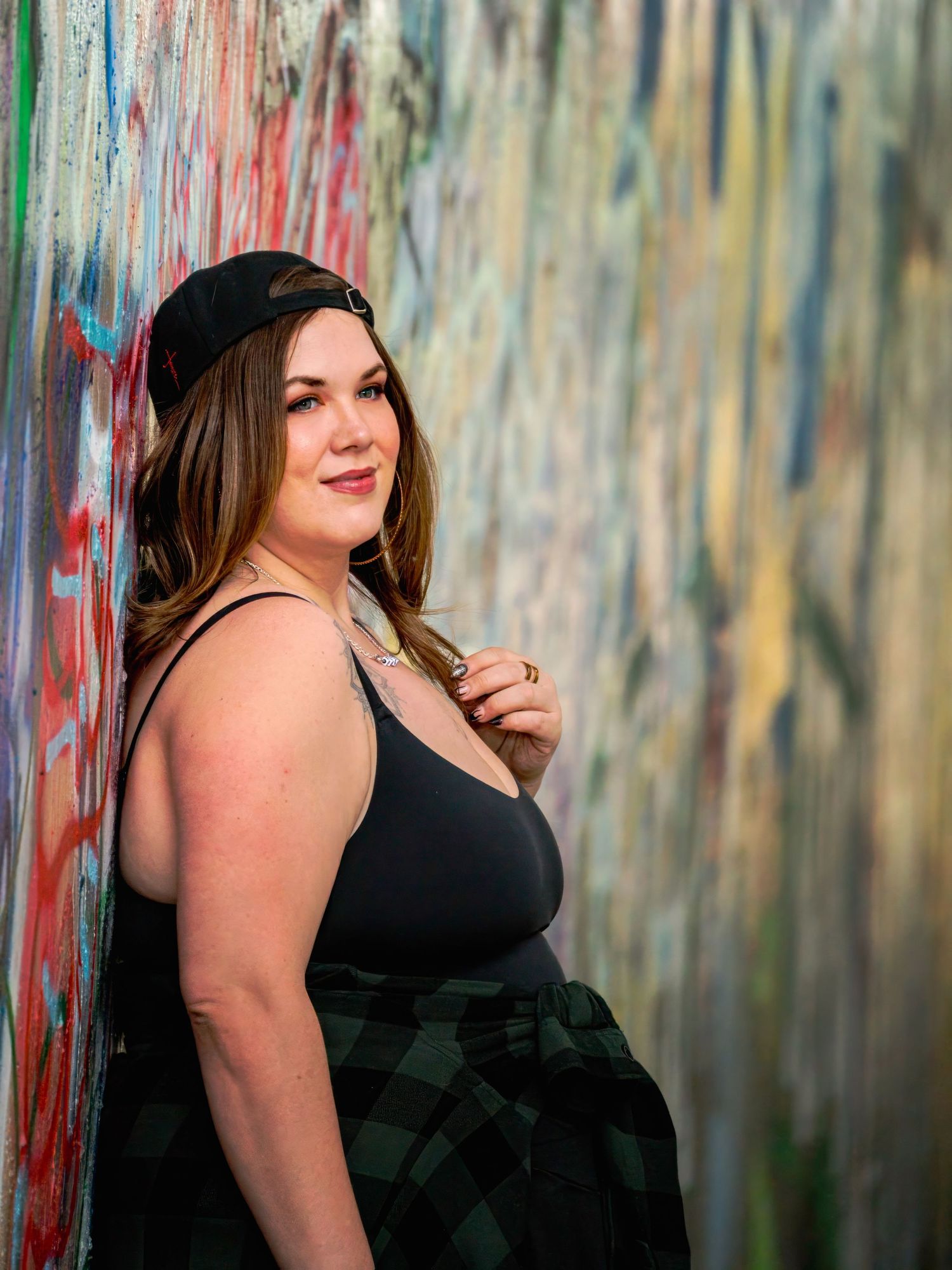 Fashion portrait against colorful graffiti wall showing elegant black outfit and confident pose.