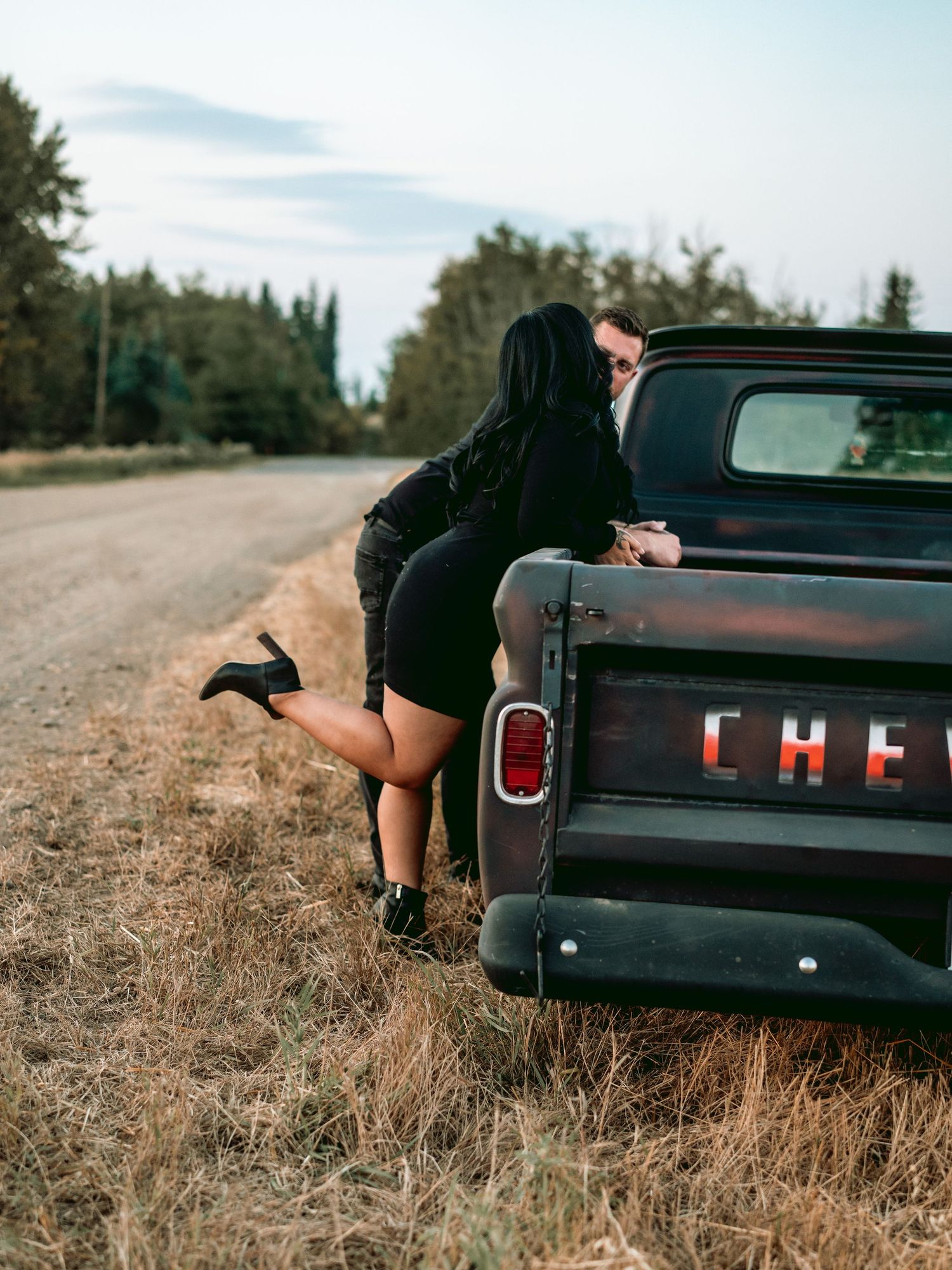 Three sequential photos showing someone playfully climbing into the back of a vintage Chevrolet pickup truck on a rural road.