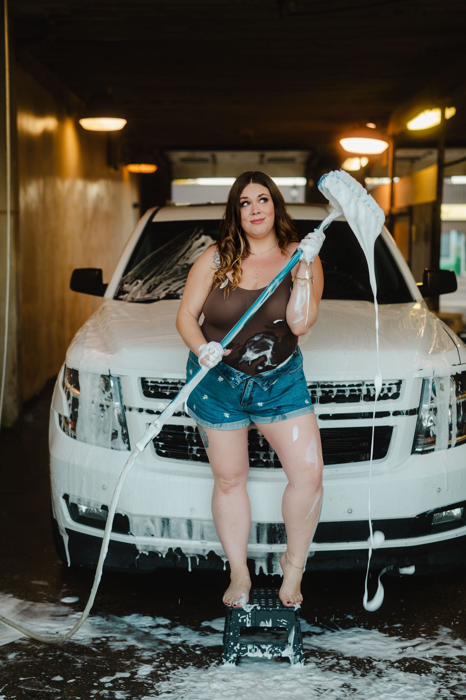 A car wash photoshoot sequence showing a white sedan being washed with soap and water in dramatic lighting.