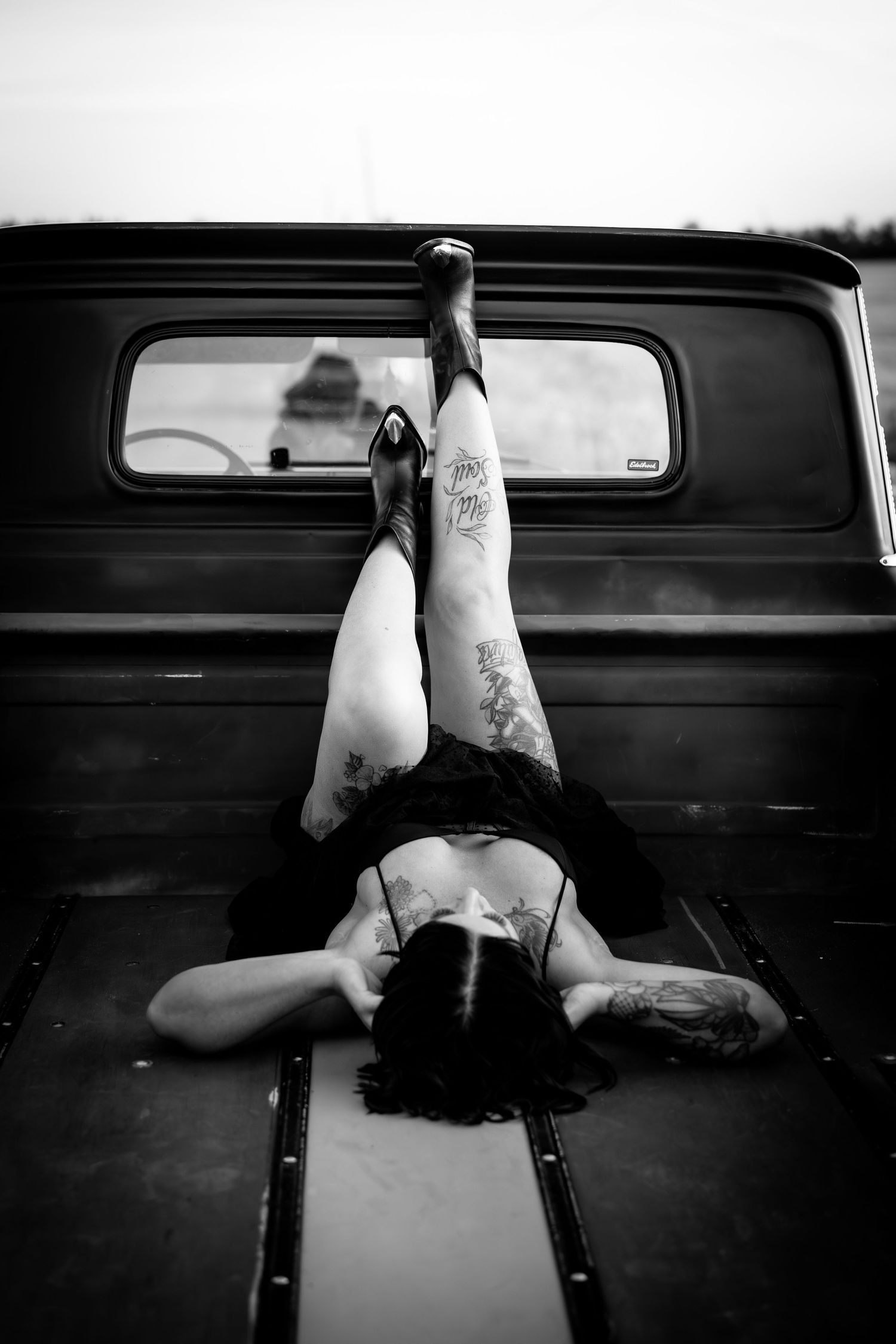 A black and white photo sequence shows a figure lying down in what appears to be the back of a vintage car.