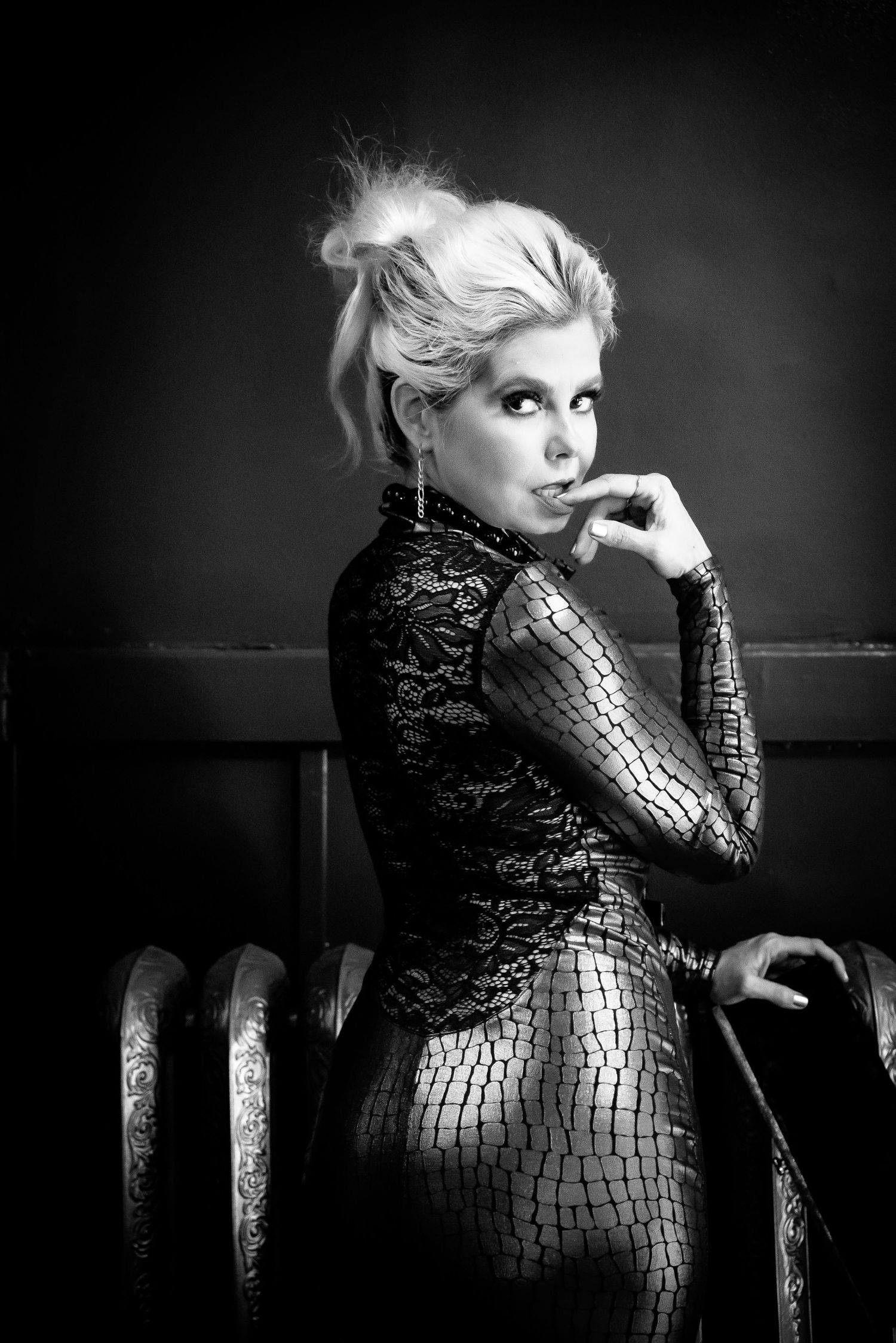 Black and white fashion portrait of a figure in a sequined dress posing dramatically against a dark background.