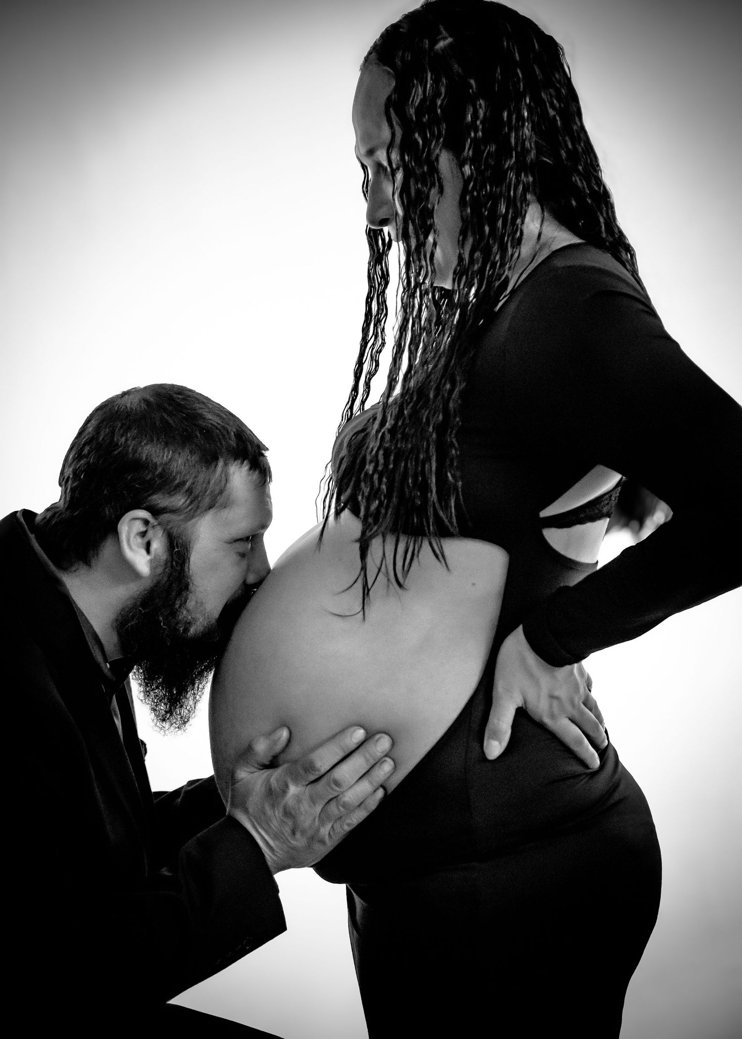 Black and white intimate maternity photo showing expectant parents during pregnancy photoshoot.