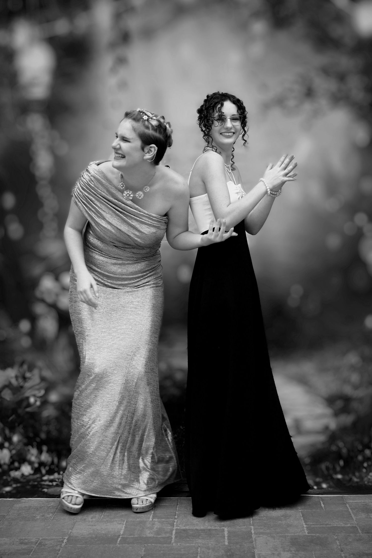 Black and white candid portrait of two sisters in formal prom dresses at a prom dinner event—natural light photography in Pace, Florida.