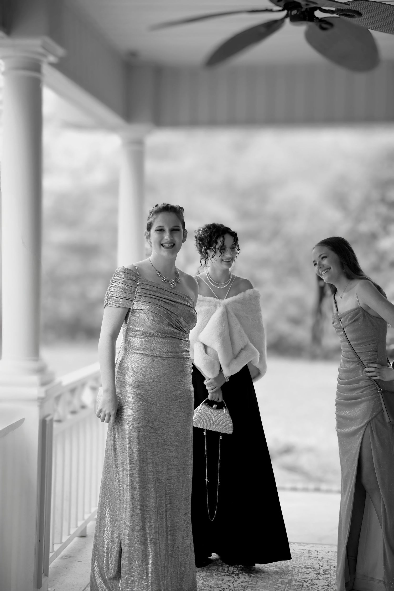 Black & white candid of three young women in formal gowns laughing—joyful, confident prom portrait in natural light by Photography by Rachel