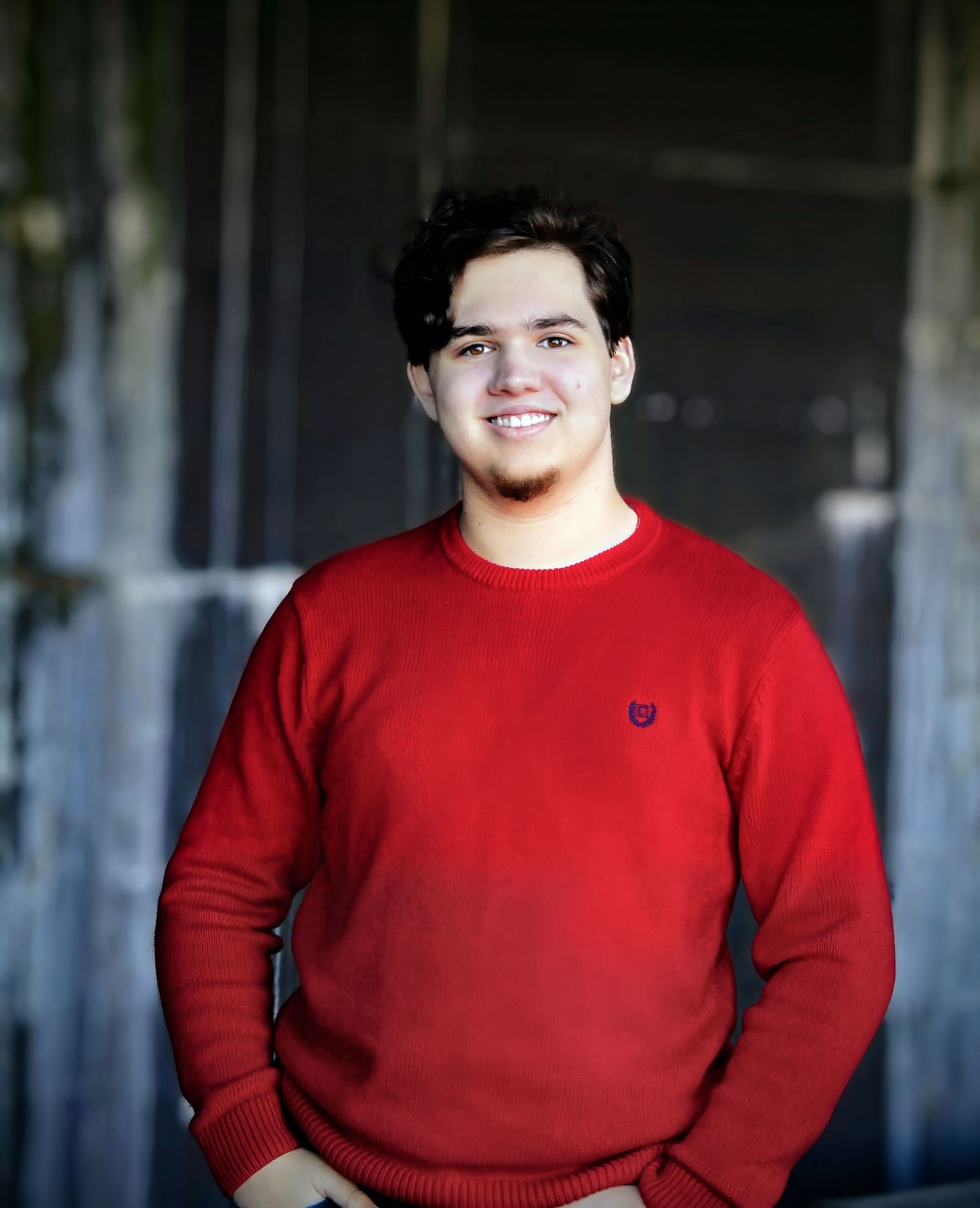 Senior portrait of smiling male in bold red sweater at Fort Pickens, Pensacola FL. Photography by Rachel