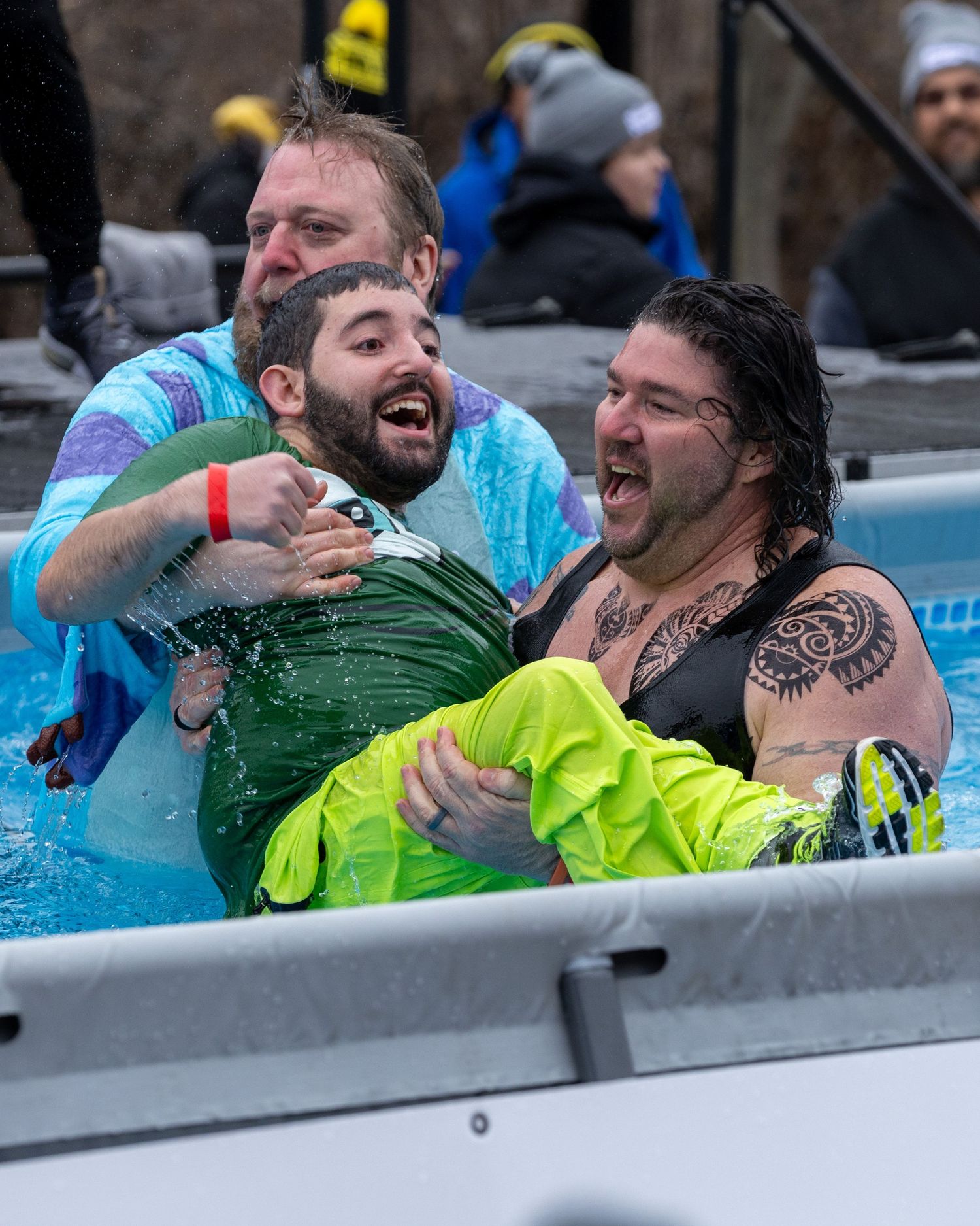 Two spectators laugh and celebrate while getting splashed with water during an outdoor sporting event.