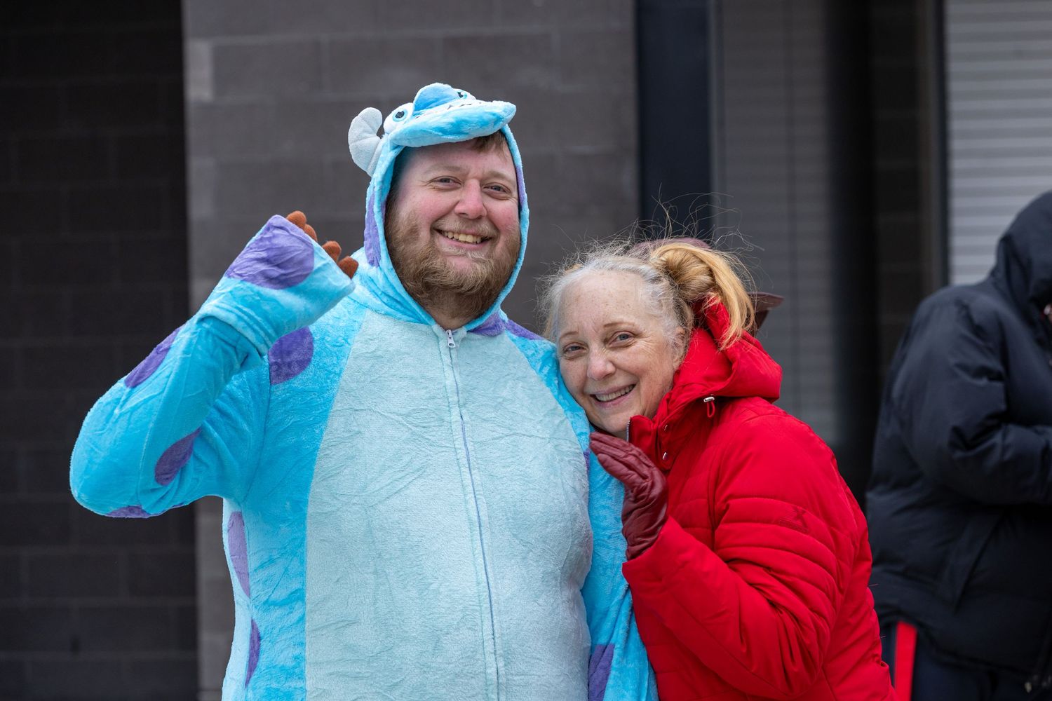 People wearing bright character costumes including a blue mascot suit and red jacket.