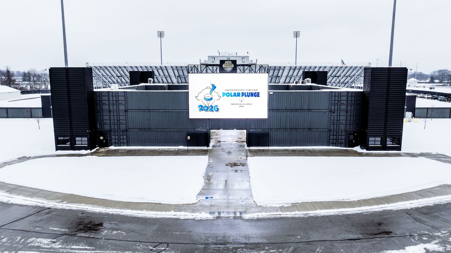 Snowy outdoor stadium with Polar Plunge event signage displayed on large screens during winter.