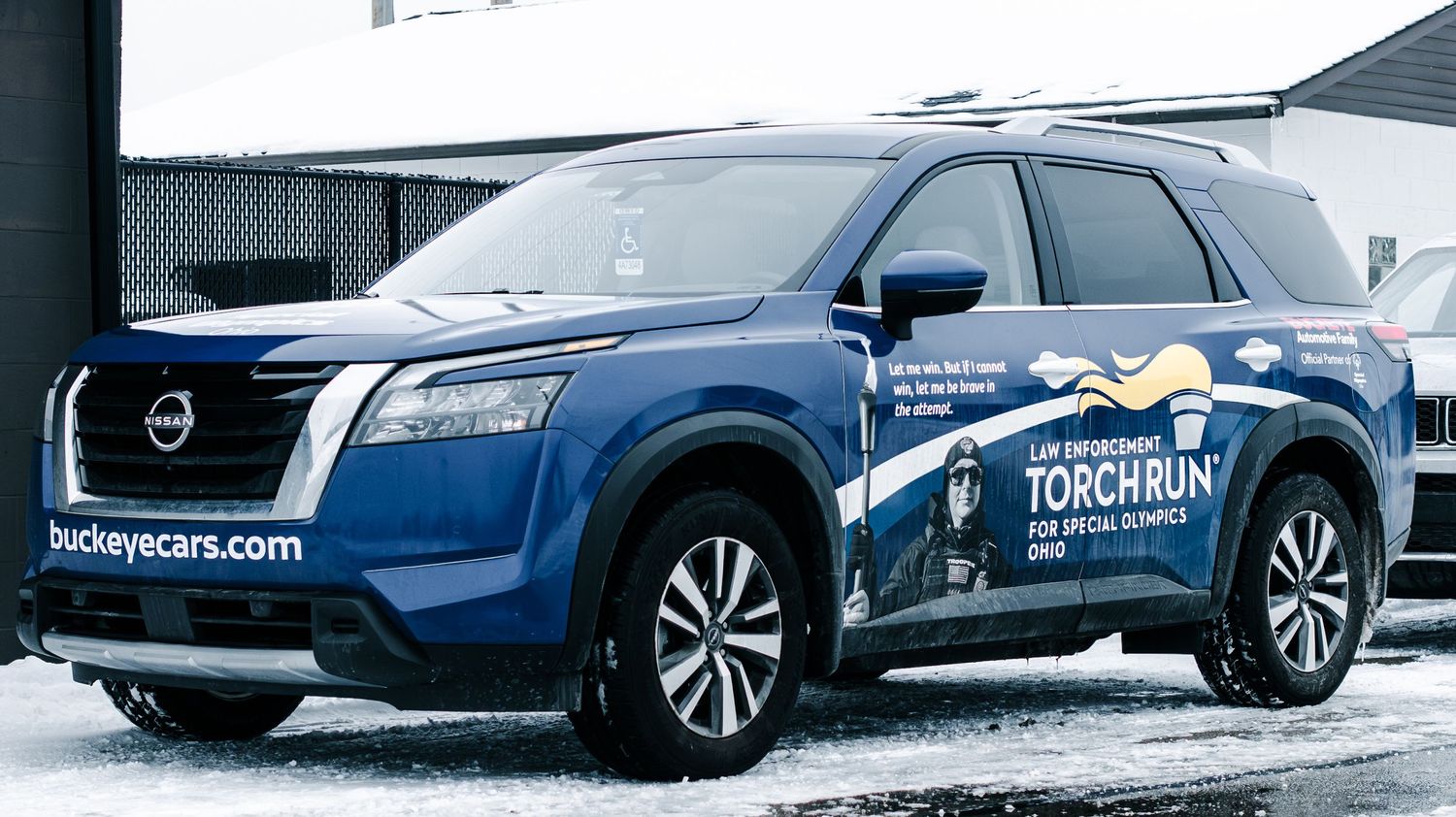 Blue Nissan Pathfinder SUV wrapped with Special Olympics Ohio Law Enforcement Torch Run branding parked outdoors.