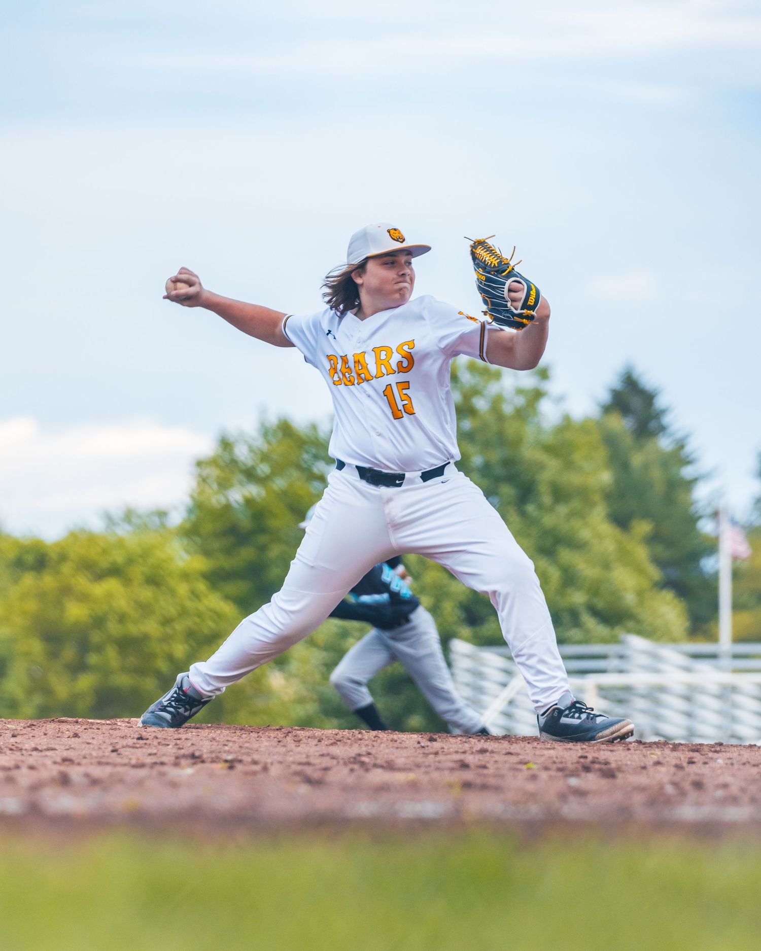 Baseball pitcher in white Mars uniform, number 15, winding up to throw on the mound during a sunny game.