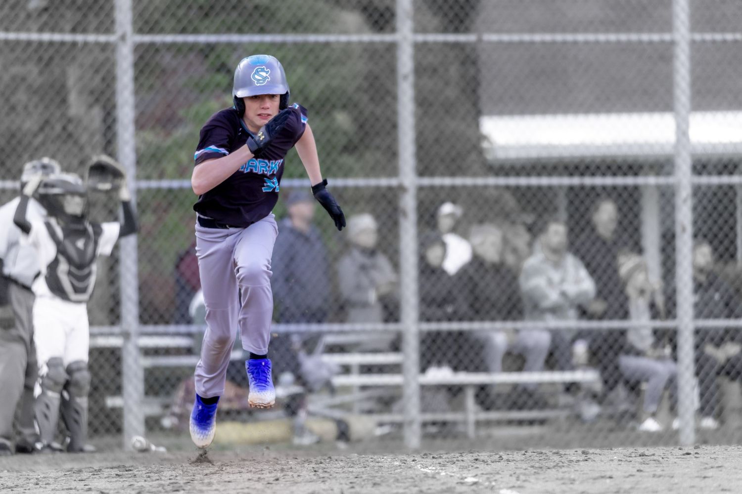 Young baseball player in blue uniform sprinting bases during a youth league game outdoors.