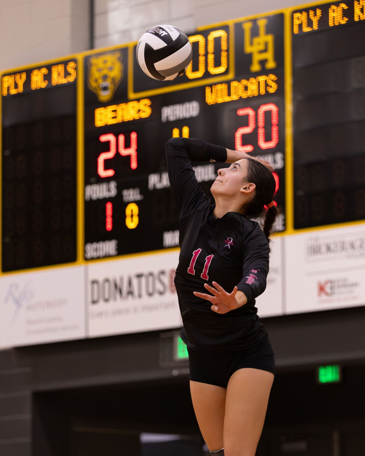 Volleyball player #11 in black jersey leaps to spike the ball during a Bears vs Wildcats game, score 24-20.