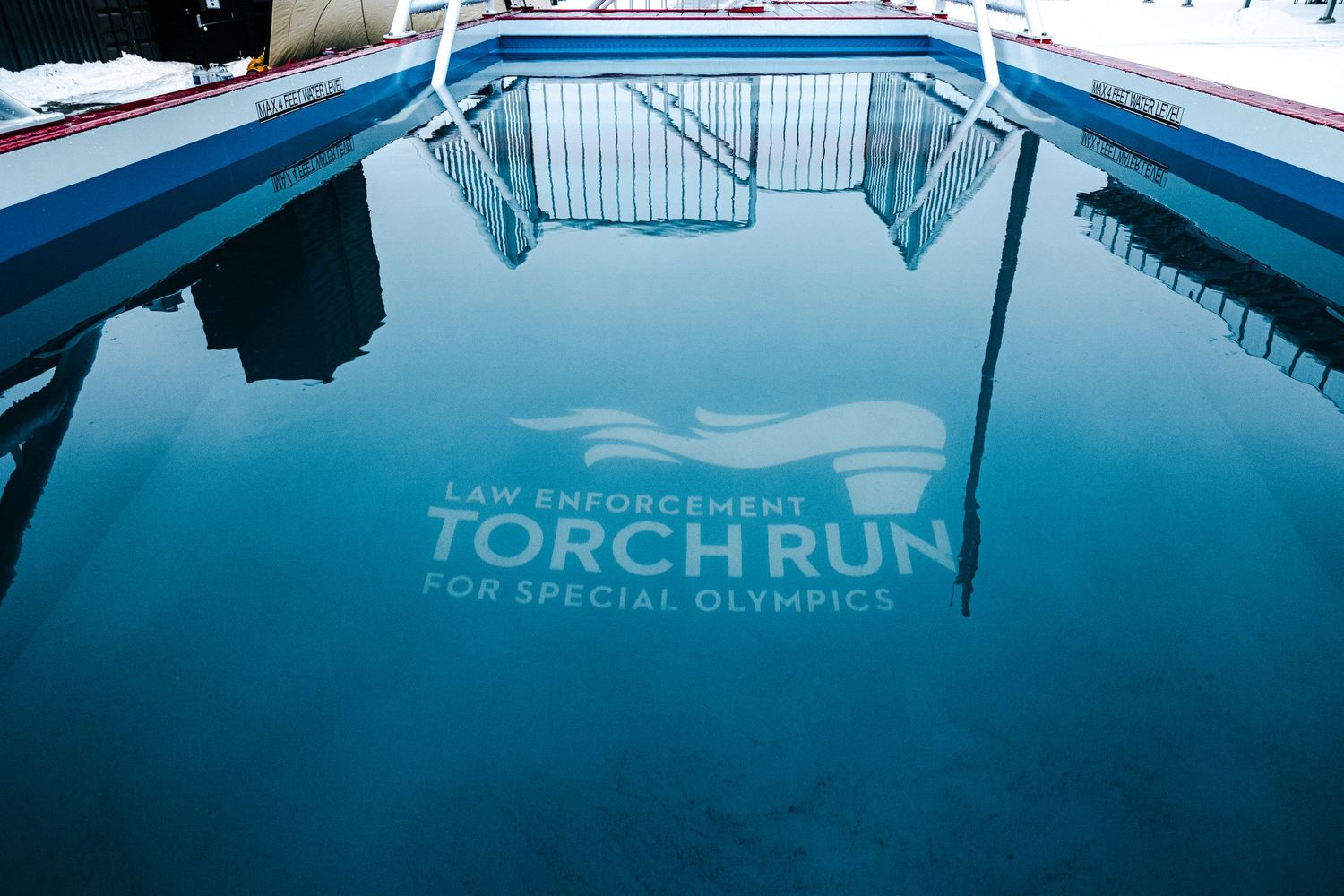 Law Enforcement Torch Run for Special Olympics logo reflected in a blue swimming pool with metal railings.