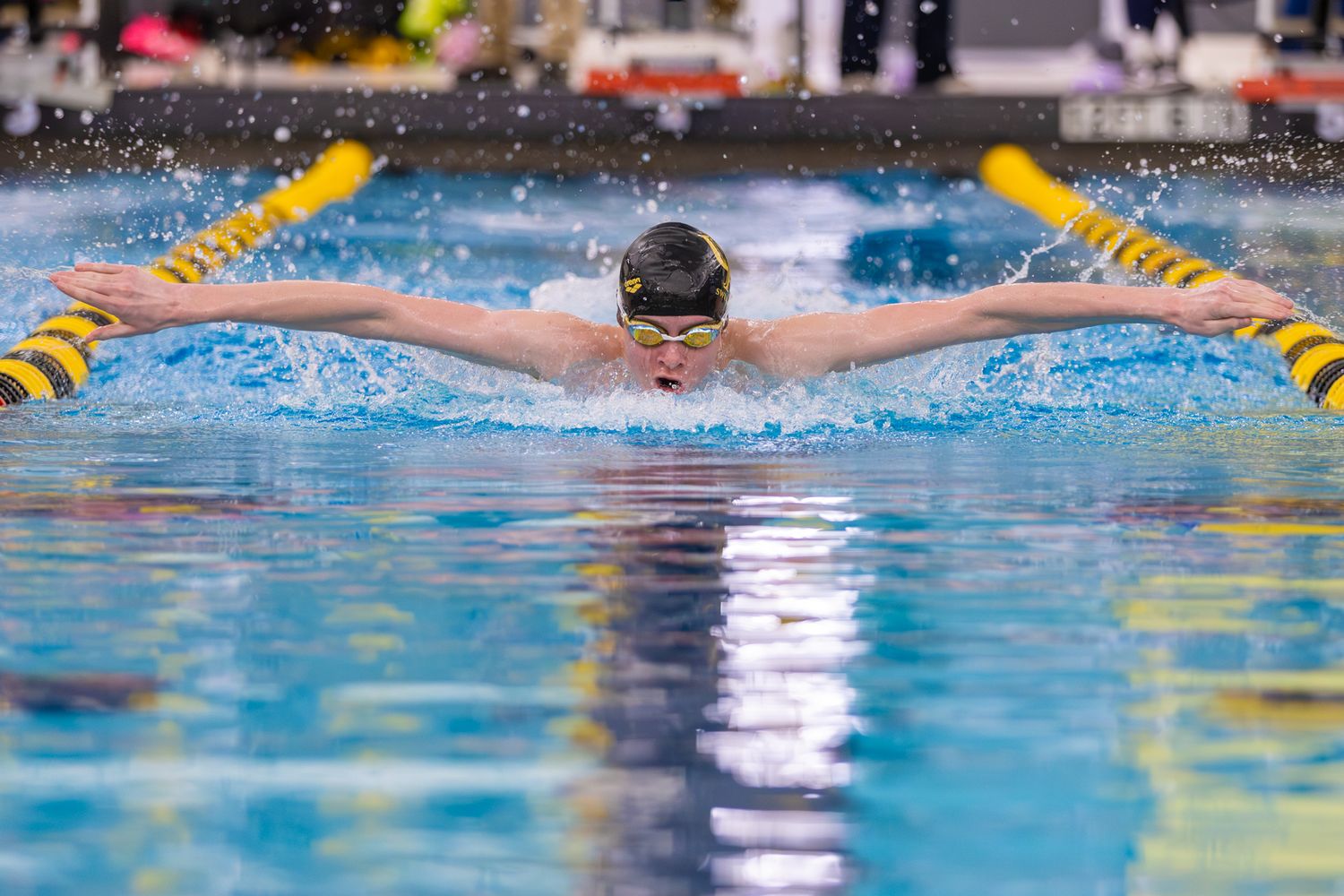 Competitive swimmer performs butterfly stroke in a pool lane during a swimming race.
