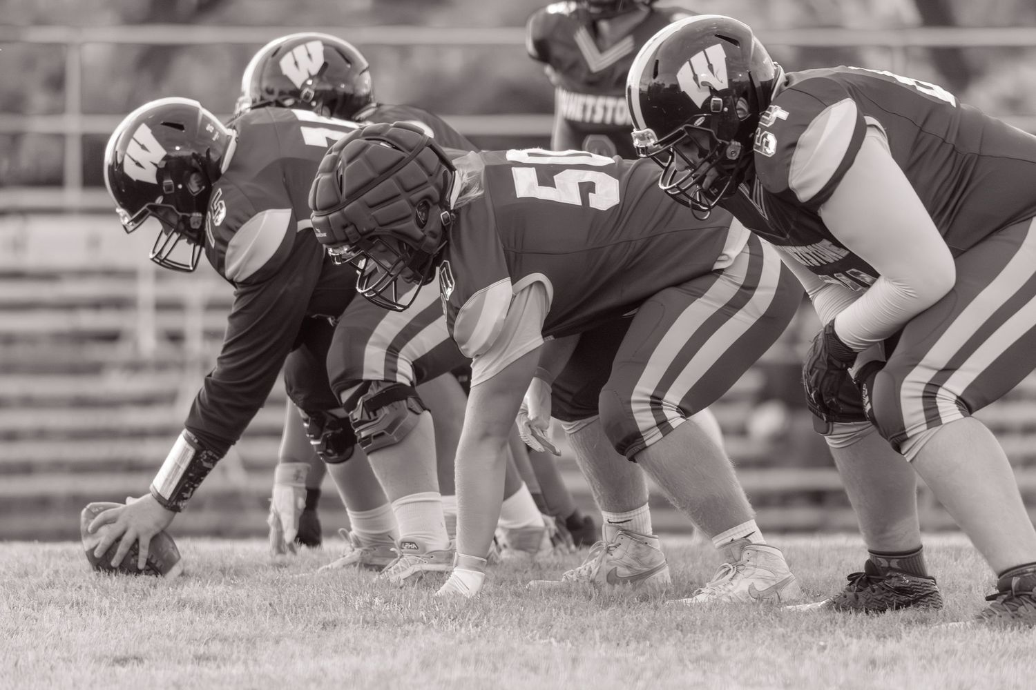 Black and white photo of high school football players lined up at the line of scrimmage during a game.