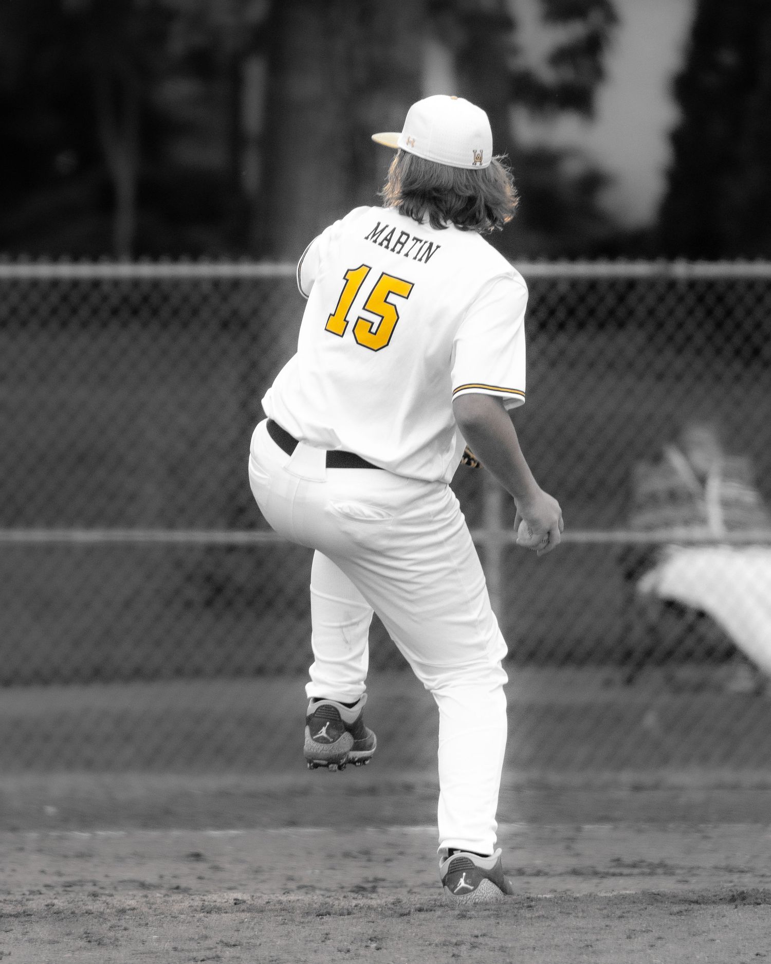 Baseball player Martin wearing jersey number 15 in white and gold uniform, captured mid-pitch in selective color photo.