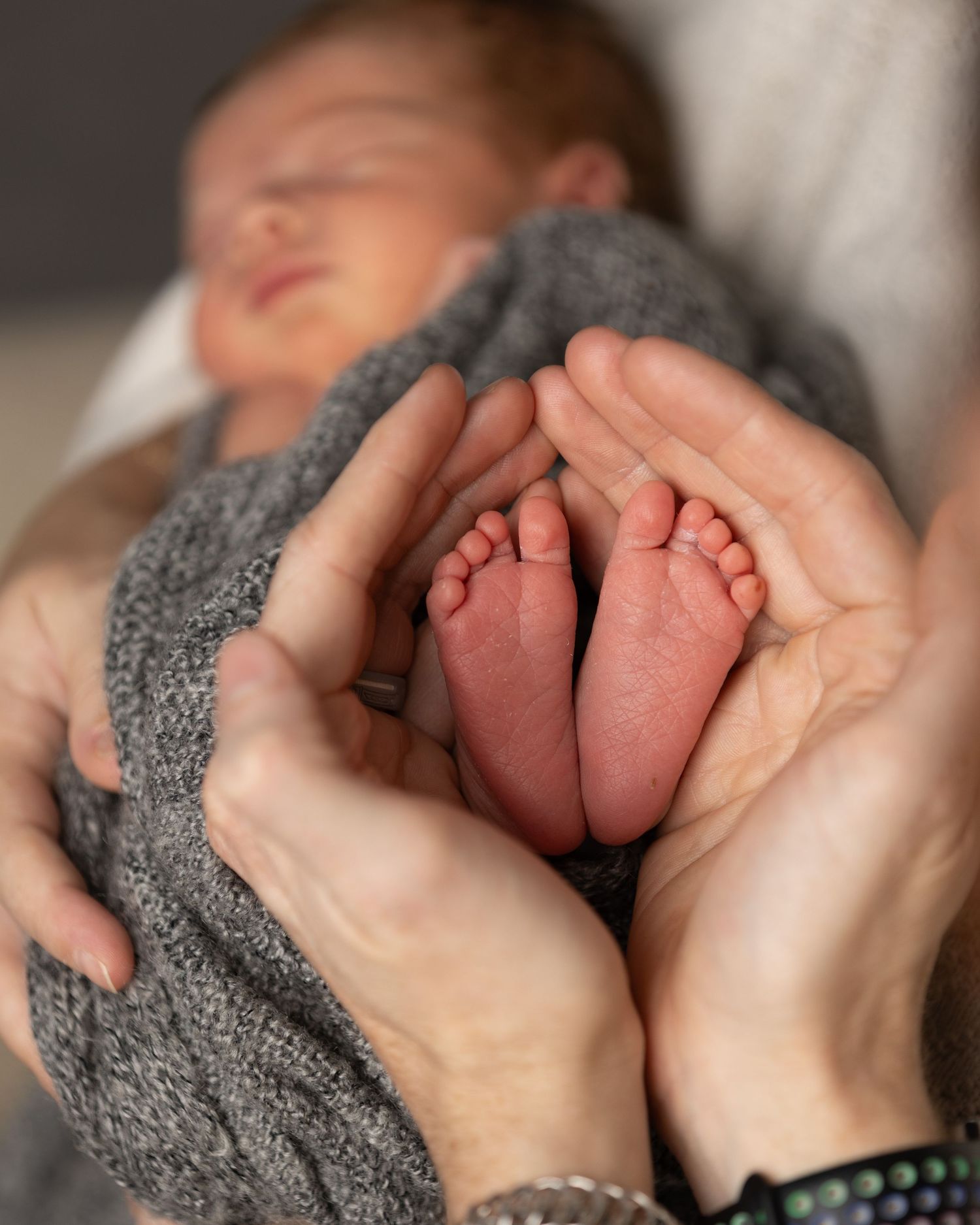 Close-up series of tiny newborn baby feet wrapped in a soft gray blanket.