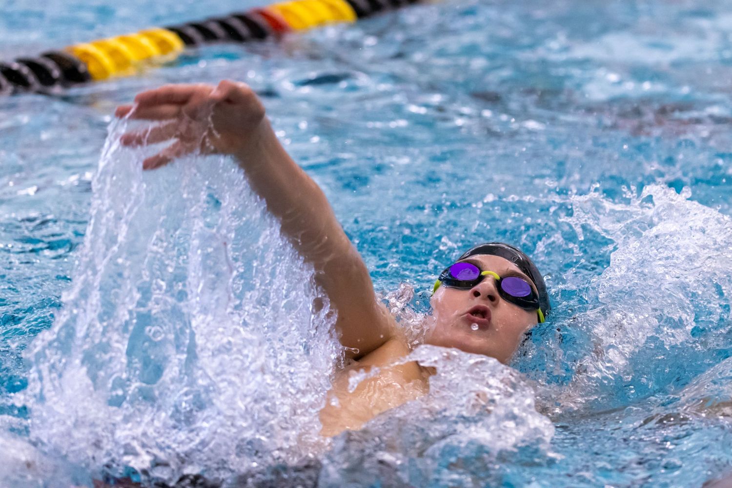 Competitive swimmer racing through pool water with dynamic splashing motion.