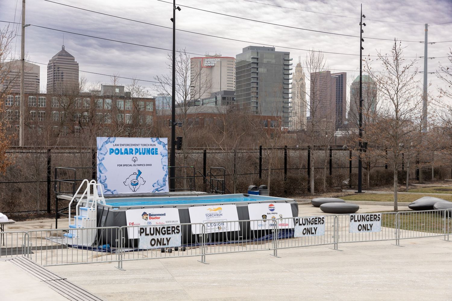 Urban skyline view with event banners and barriers set up for a polar plunge fundraiser.
