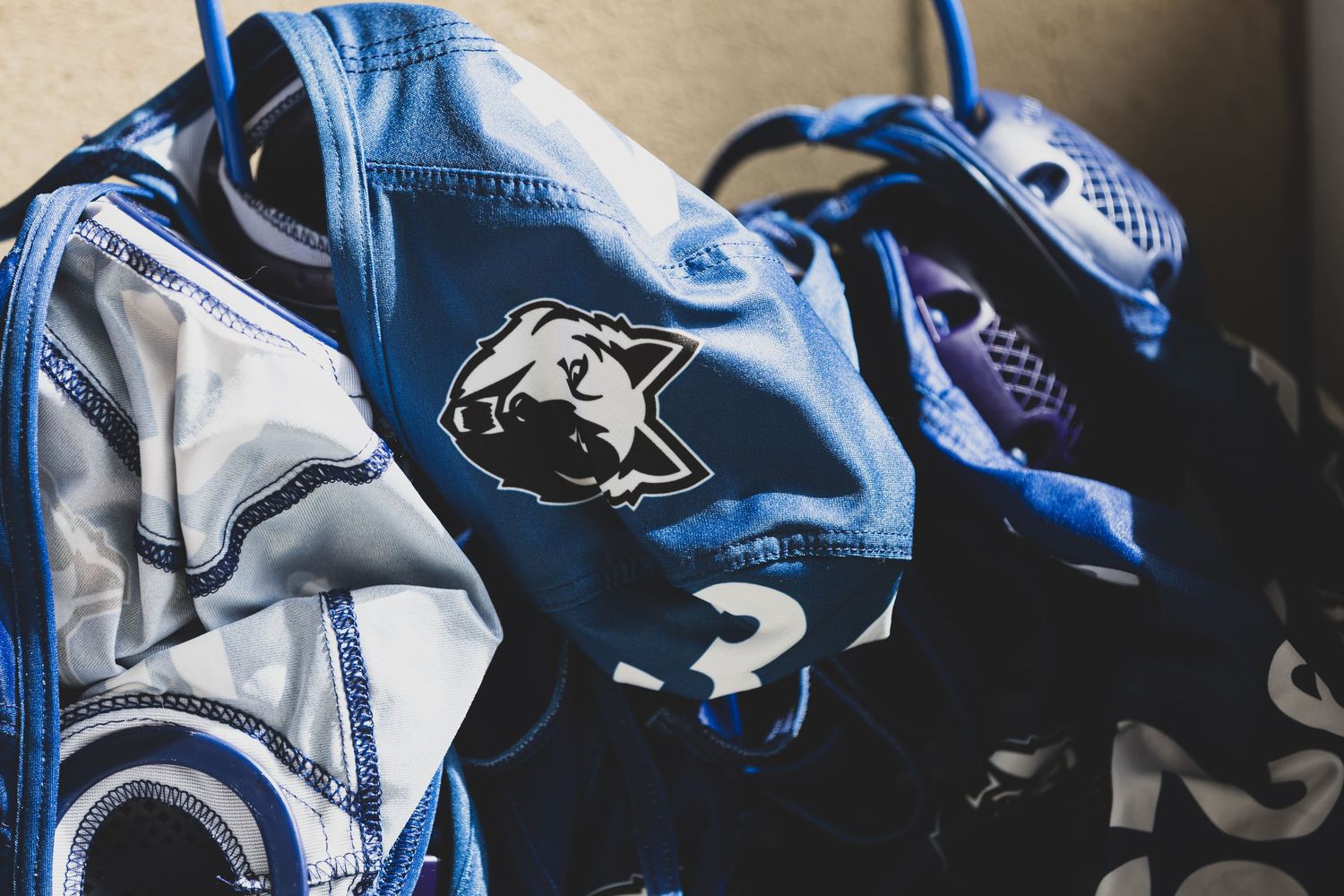 Blue varsity jacket with a bear mascot patch displayed alongside sports gear and accessories.