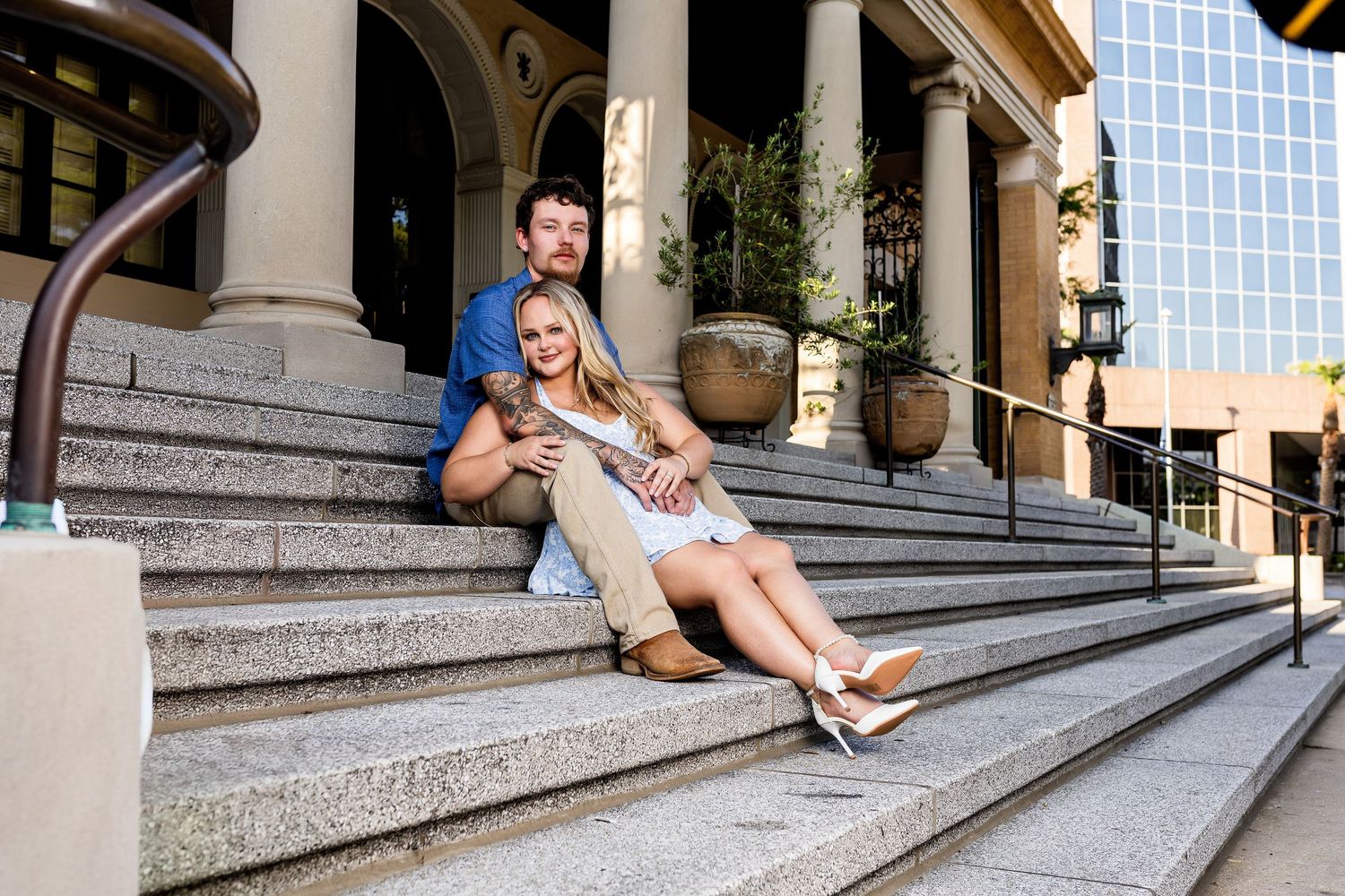 Couple relaxing on outdoor stone steps of an urban building on a sunny day.