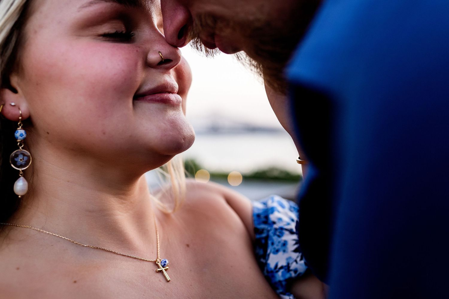 An intimate close-up captures a romantic moment with dangling silver earrings and a cross necklace in view.