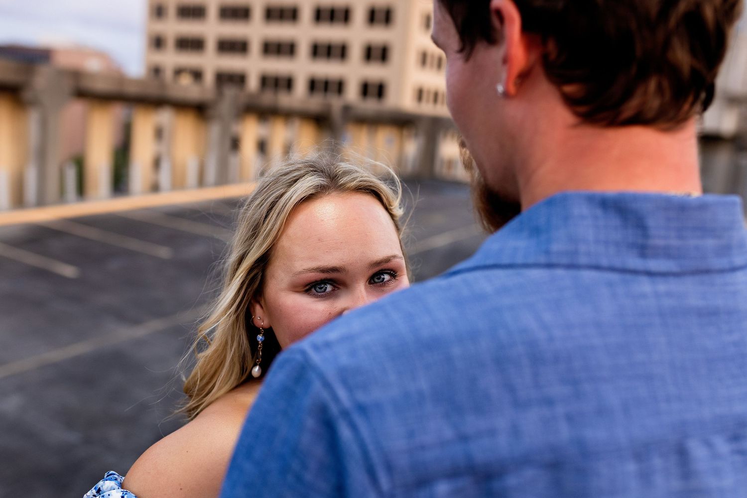 A romantic moment captured on an urban rooftop with soft lighting and denim clothing.