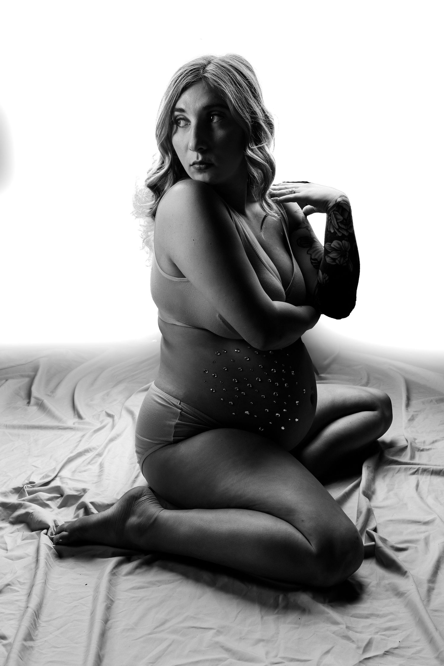 Black and white artistic boudoir photograph with dramatic lighting and rhinestone accented bodysuit.