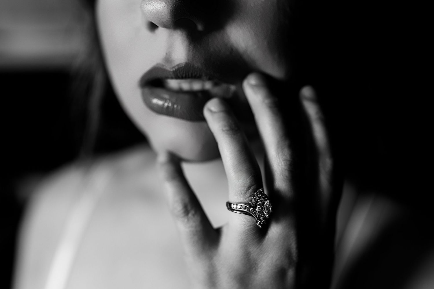 Black and white close-up photo of a smiling mouth showing teeth and wearing lipstick.