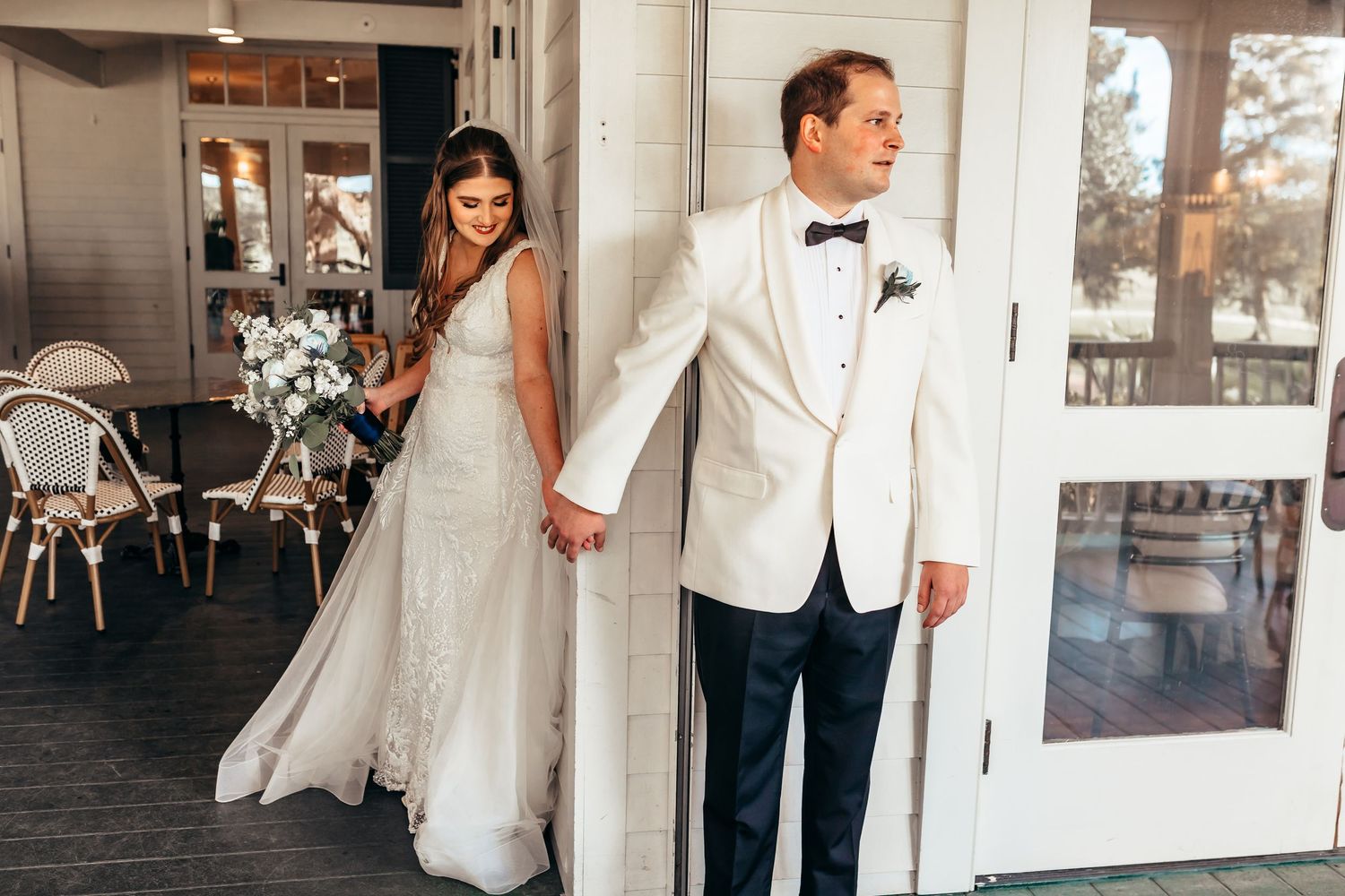 A couple shares a sweet first look moment before their wedding ceremony, with the bride in white and groom in ivory jacket.