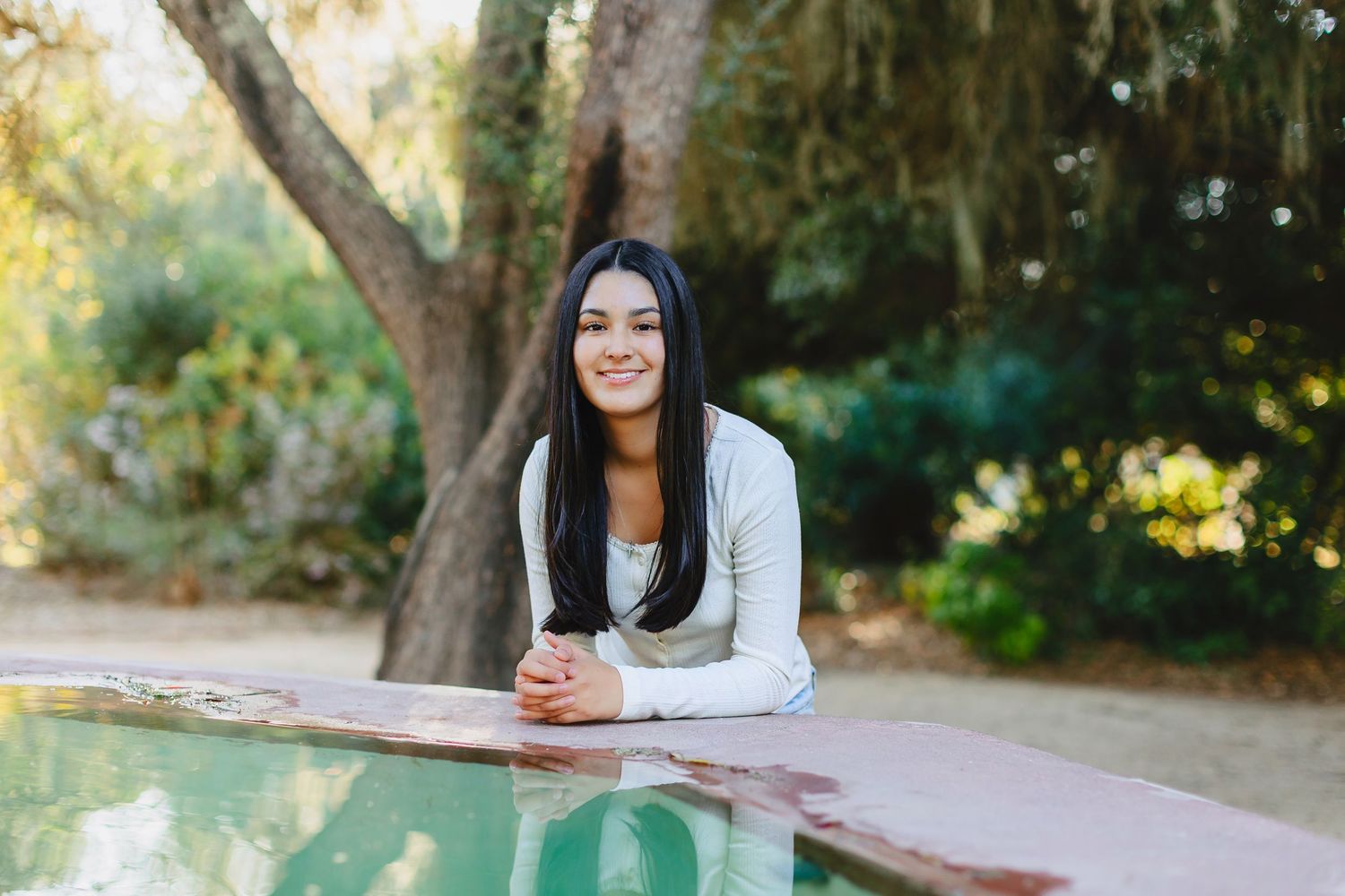 Woman in white sweater relaxing outdoors at rustic wooden table on sunny autumn day.
