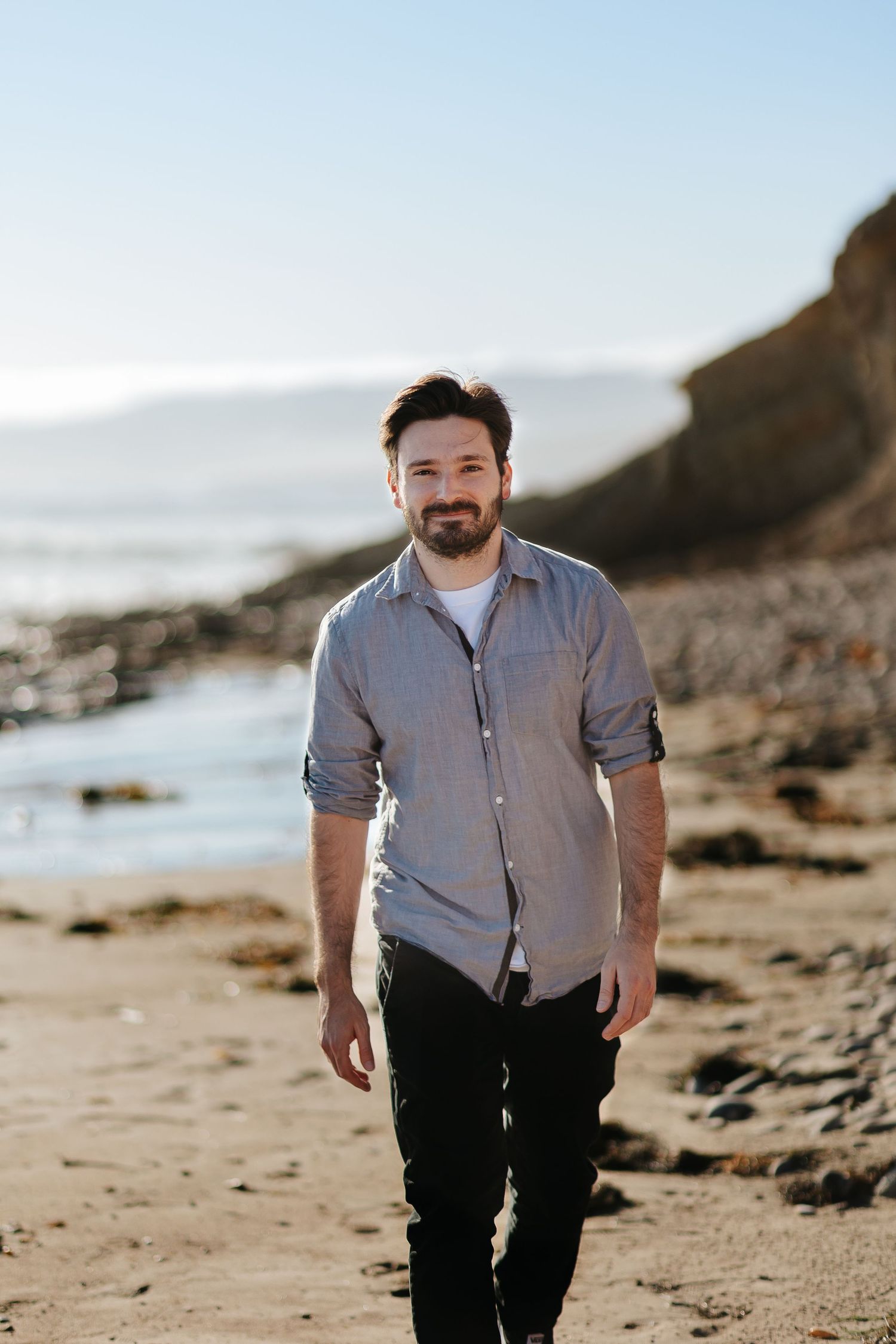A casual portrait at a rocky beach coastline on a sunny afternoon.
