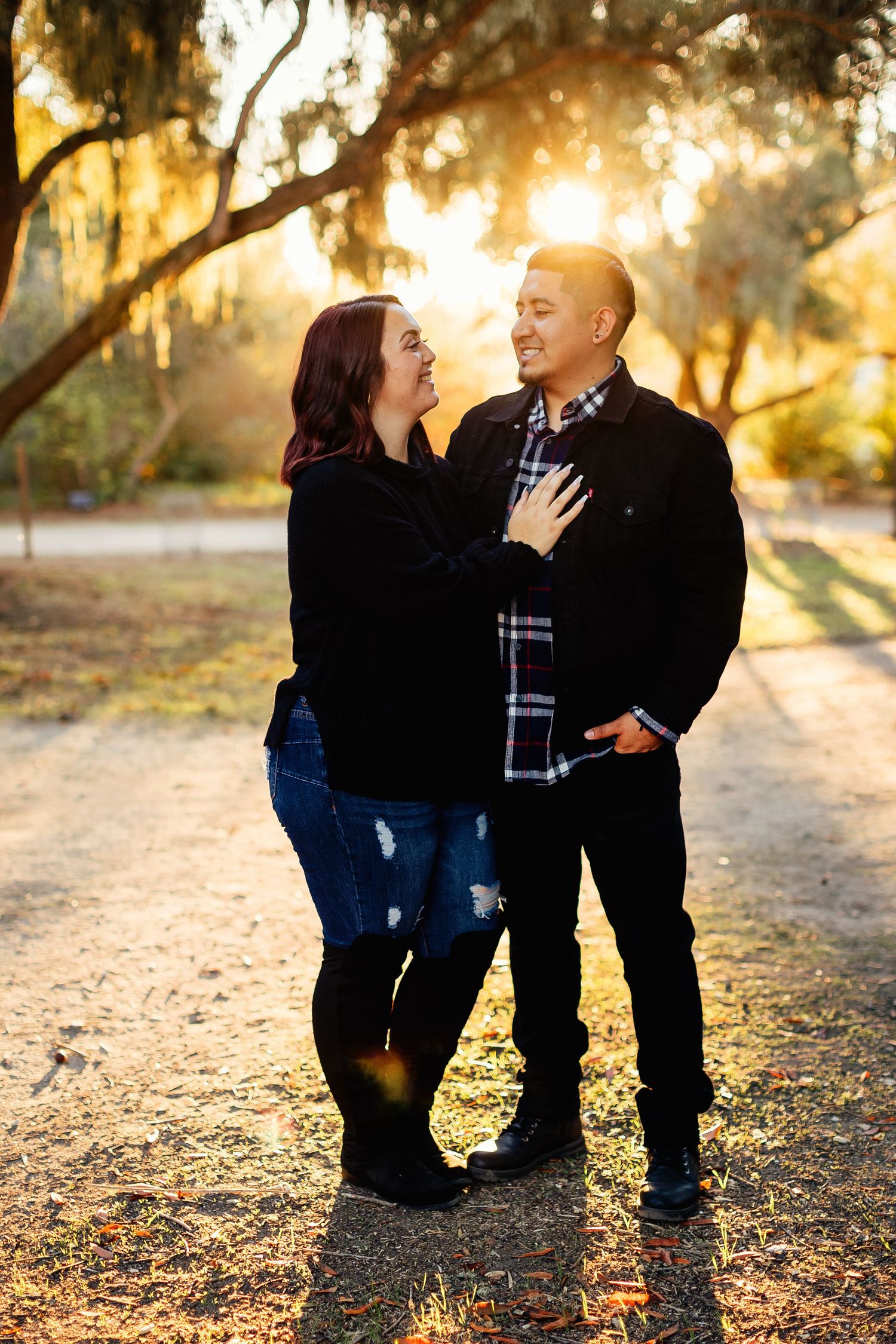 Parent kneels down to embrace young child in autumn outdoor setting with golden sunlight filtering through trees.