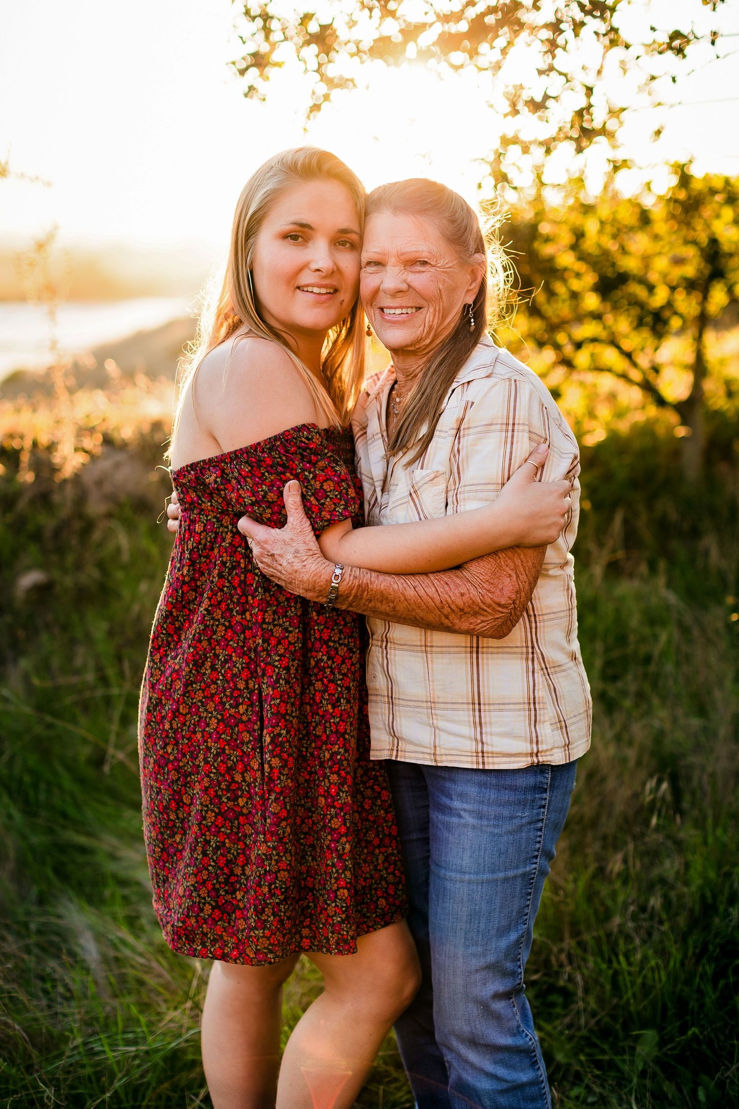 Pair embracing during golden hour photoshoot outdoors with natural sunlight and greenery.
