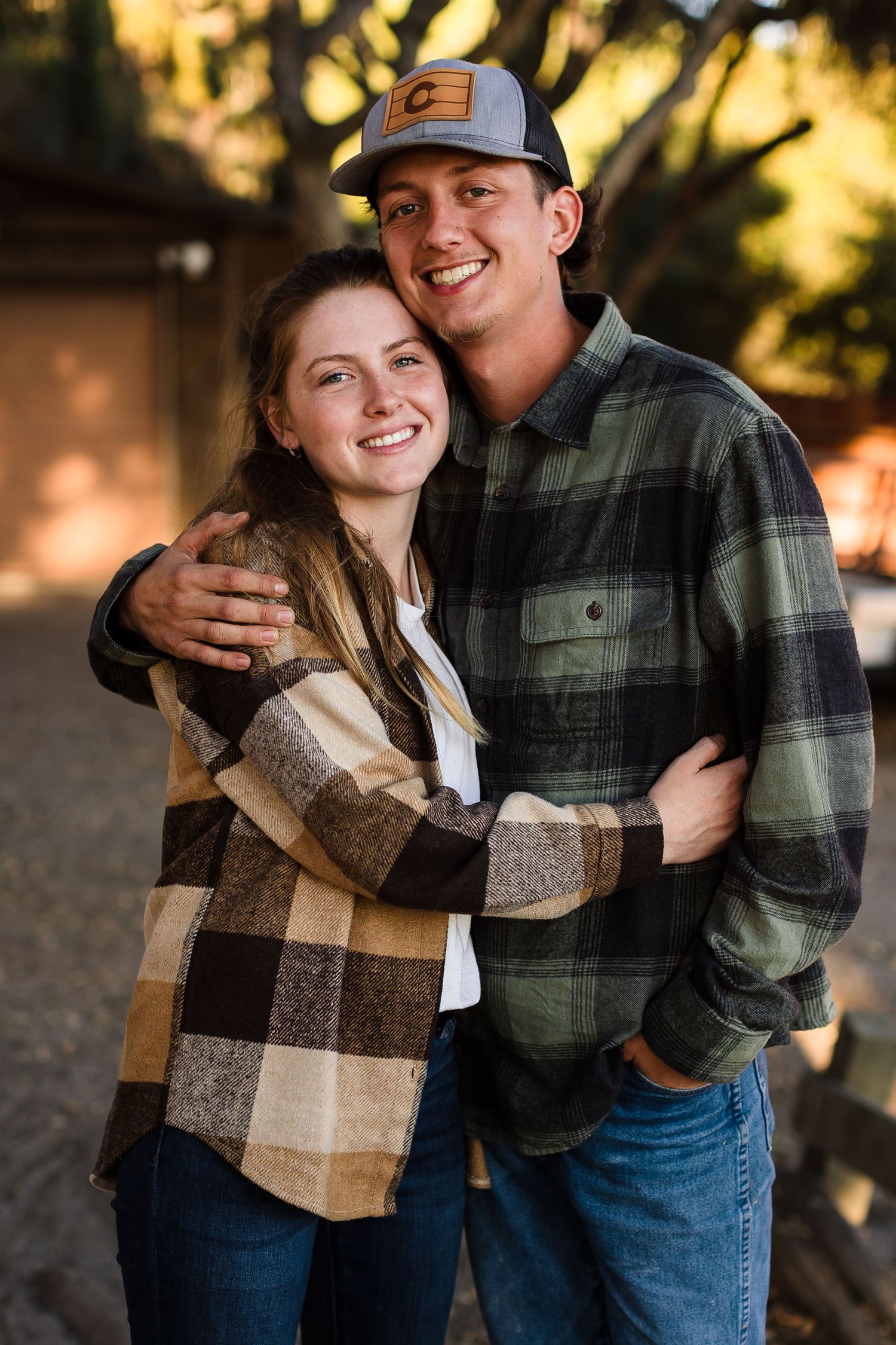 A couple shares an intimate embrace outdoors while wearing casual flannel and denim on an autumn evening.