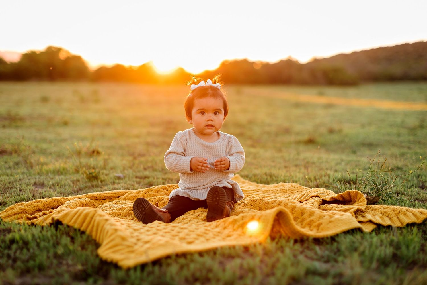 A series of outdoor sunset photographs showing someone on a yellow blanket in a grassy field during golden hour.